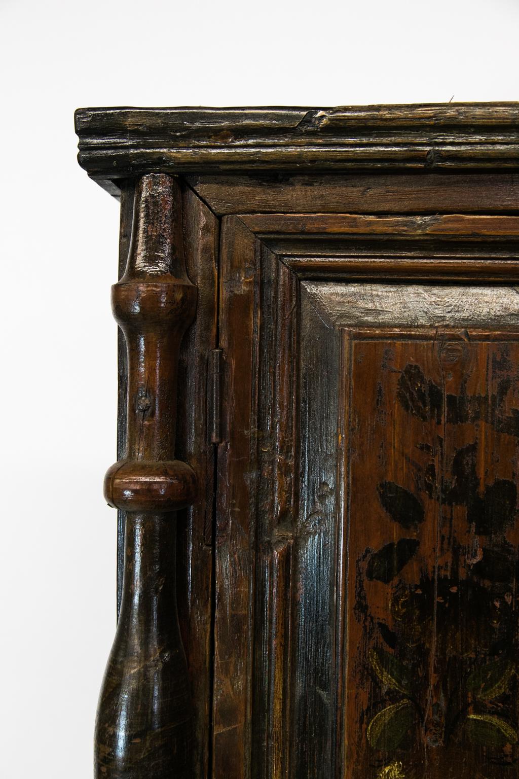 Central European painted step back cupboard, has exposed dovetail construction. The drawers are painted with potted floral motifs, and a stylized cat and dog are painted on the sides. The top section has spindles applied to the chamfered corners.