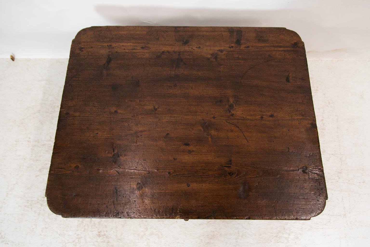 The top of this pine coffee table has ovolo shaped corners and support cleats dovetailed into the underside of the top. The legs have double exposed peg construction and are connected at the bottom by a shaped cross stretcher. The top is not