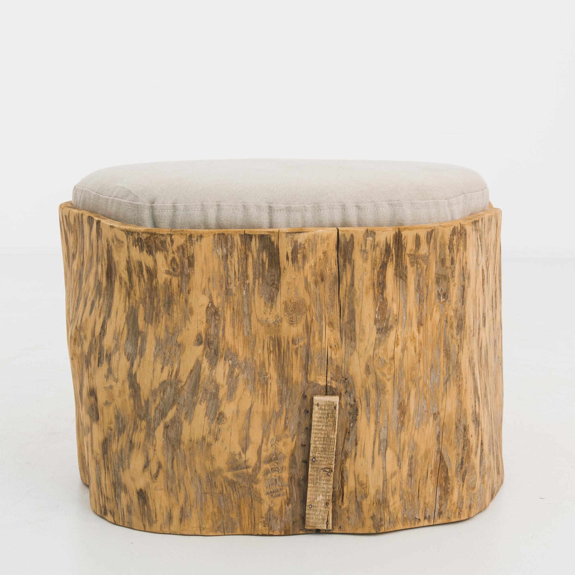 This antique wooden pouf was made in Poland. Crafted from a tree trunk, the smooth patina and variegated tones of gray and flaxen offer warmth and a rustic charm. Accompanied by a newly upholstered cushion in an ecru shade for comfort and style.