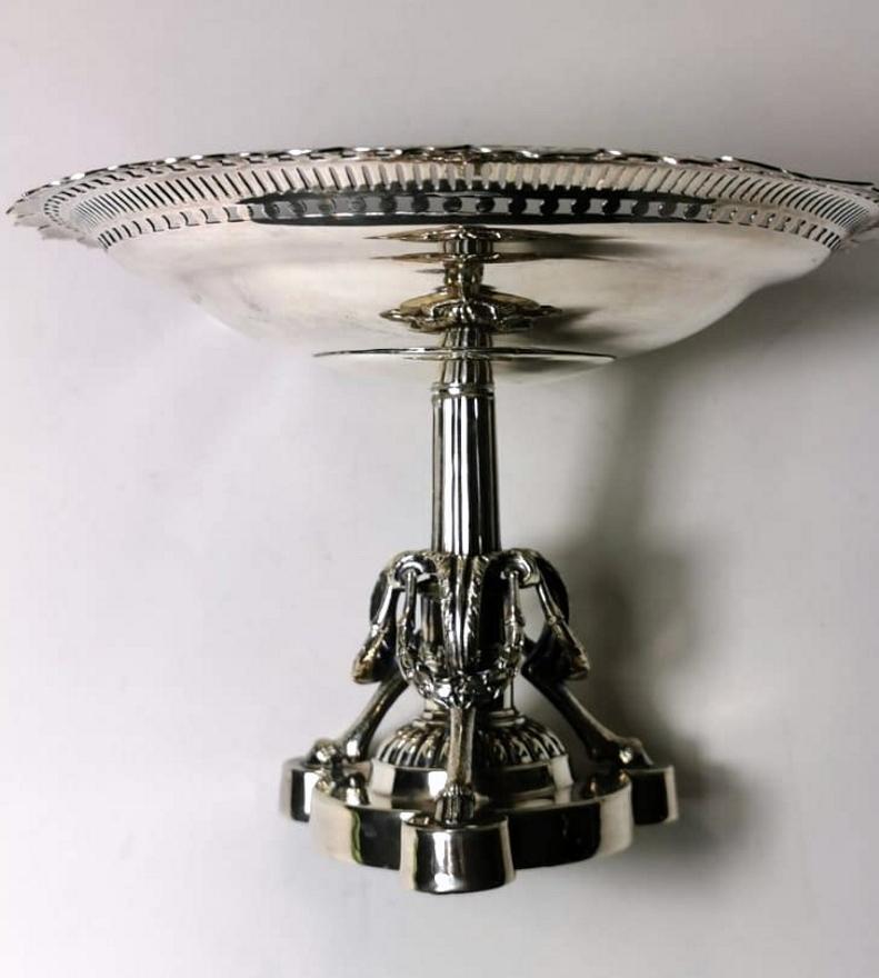 A Victorian centerpiece in silver plated; the base, made with an exceptional fusion, is very elaborate with goat's paws and garlands; the grooved stem supports a plate worked with an elegant fretwork surrounded by a beautiful and detailed