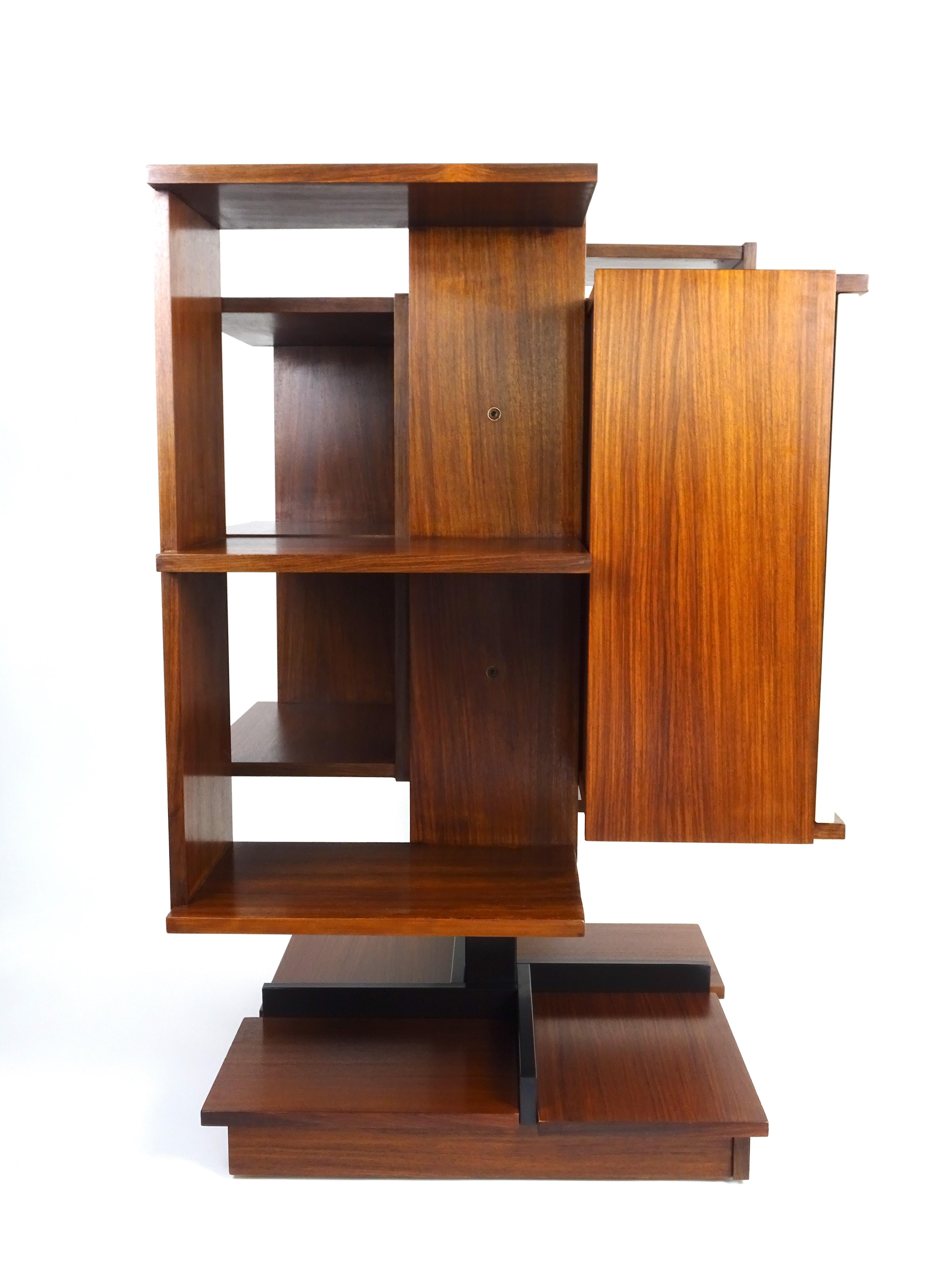 Modular and revolving bookcase in wood veneer with central support in lacquered metal. This vintage item has no defects, but it may show slight traces of use.
