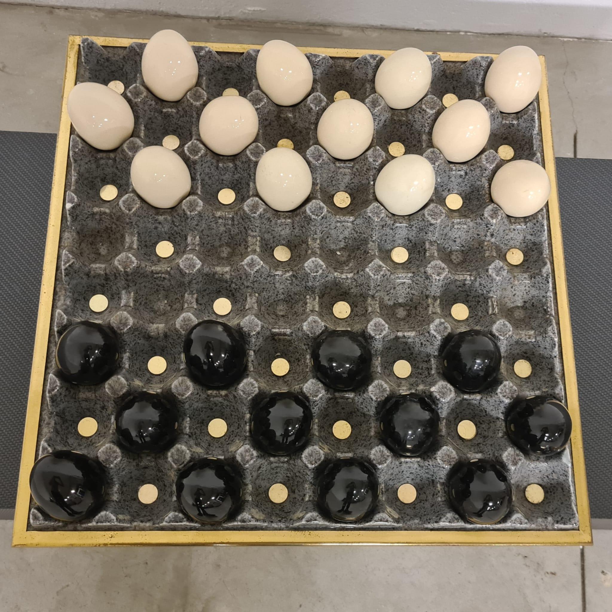 Centerpiece/sculpture by Desart Mabizaf

Eccentric checkers made as egg carton in ceramic and brass.

Refined and fun this sculpture consists of the base i.e. an egg-holder plato and twenty-four eggs.

Ideal as a table centerpiece or decorative