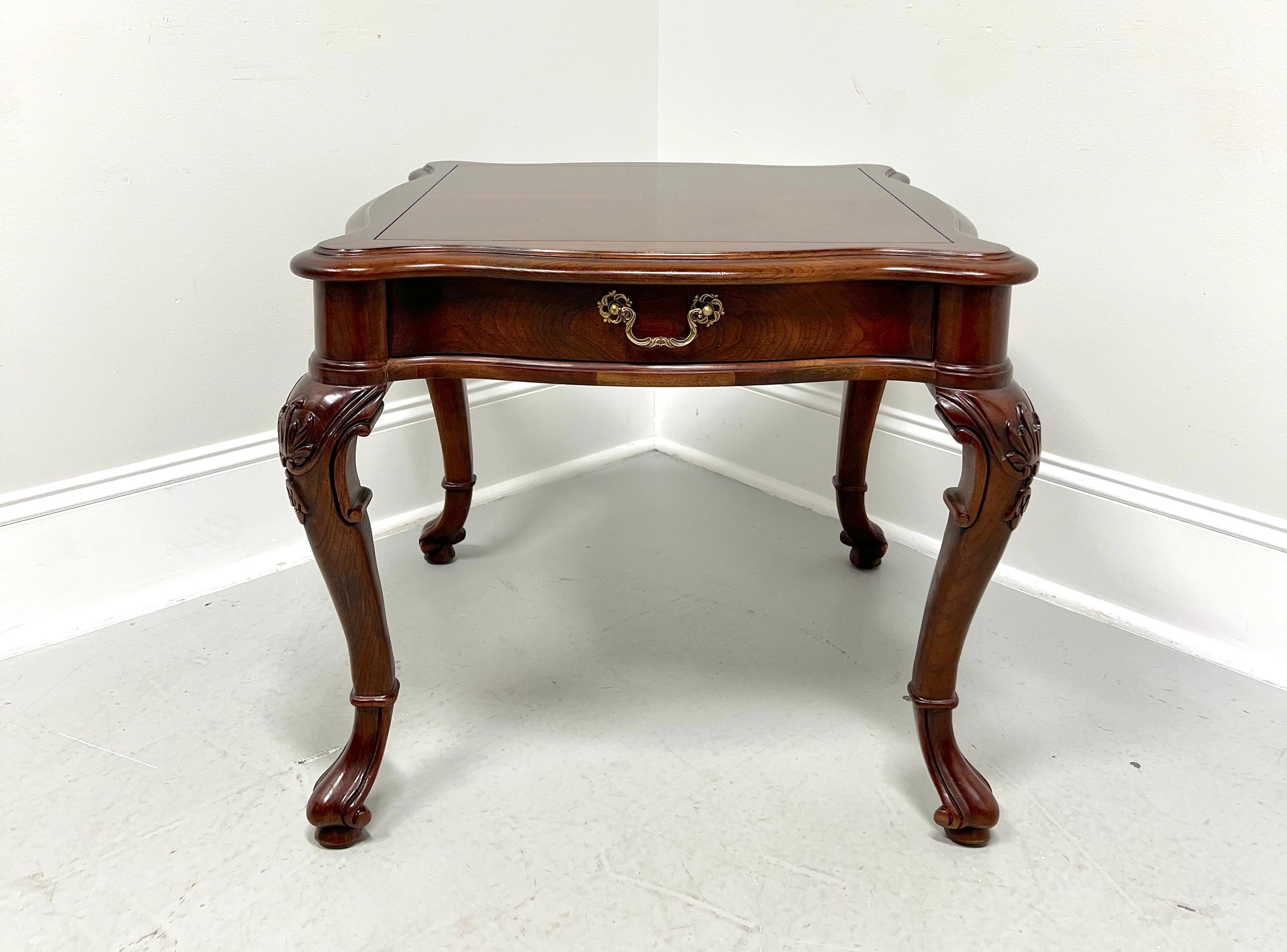 An Italian Provincial style lamp table by Century Furniture, from their Cardella Collection. Cherry wood with decorative brass hardware, banded top with bevel edge & rounded corners, serpentine shape, finished on all sides, carved knees, cabriole