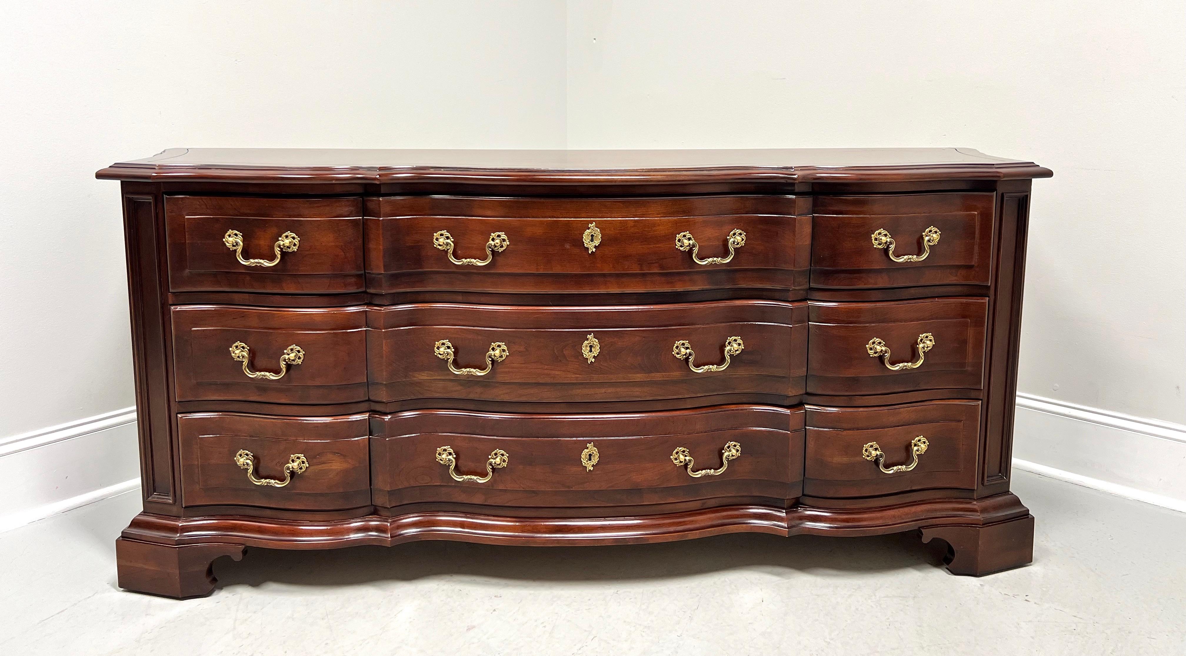 An Italian Provincial style triple dresser by Century Furniture, from their Cardella Collection. Cherry wood with decorative brass hardware, banded top with bevel edge & squared corners, serpentine shape, raised drawer fronts, and bracket feet.