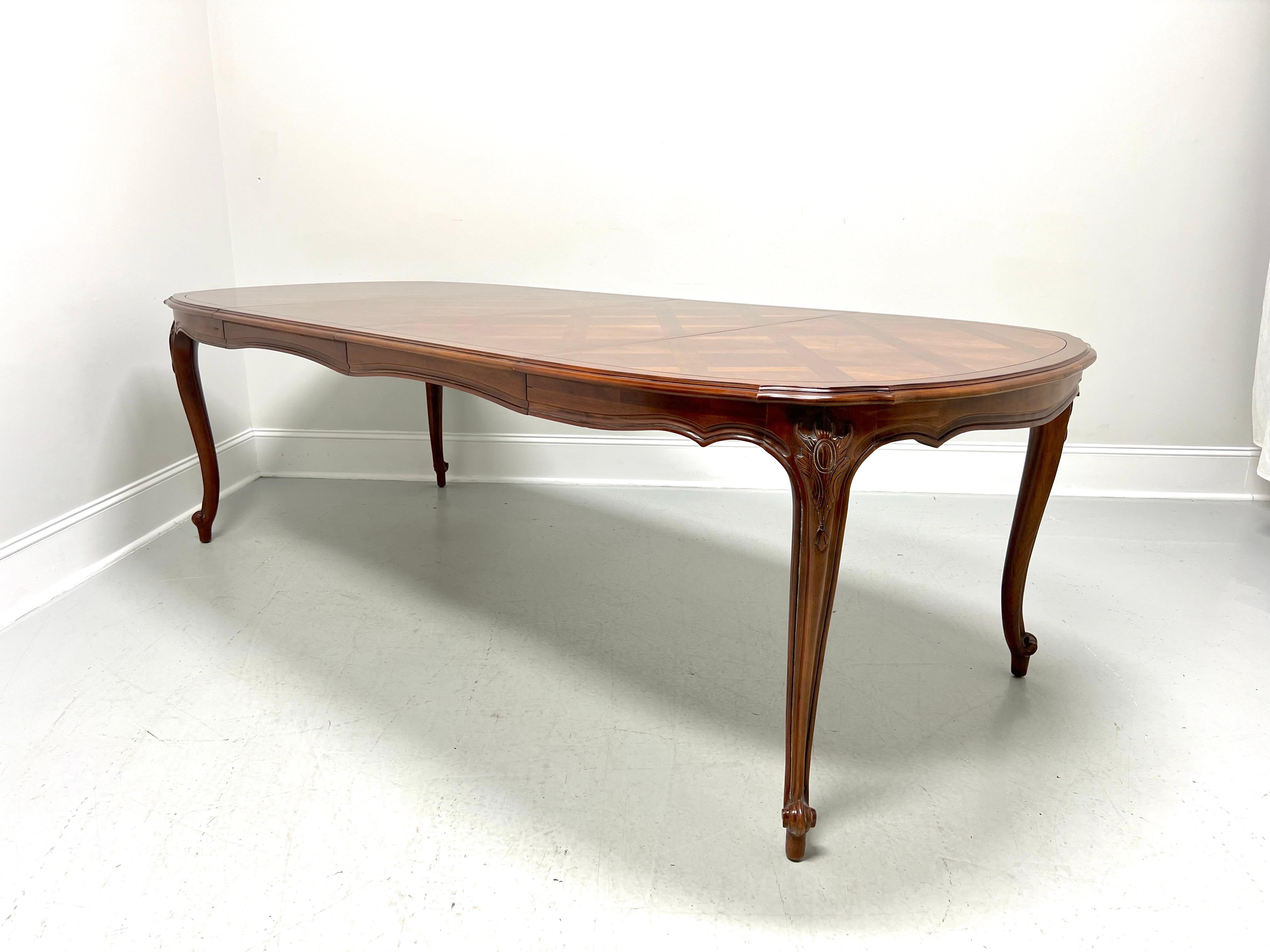A French Provincial style oval dining table by Century Furniture, from their Chardeau Collection designed by Raymond K Sobota. Cherry wood with veneers, banded diamond-shaped parquetry top with a beveled serpentine edge, carved apron, decoratively