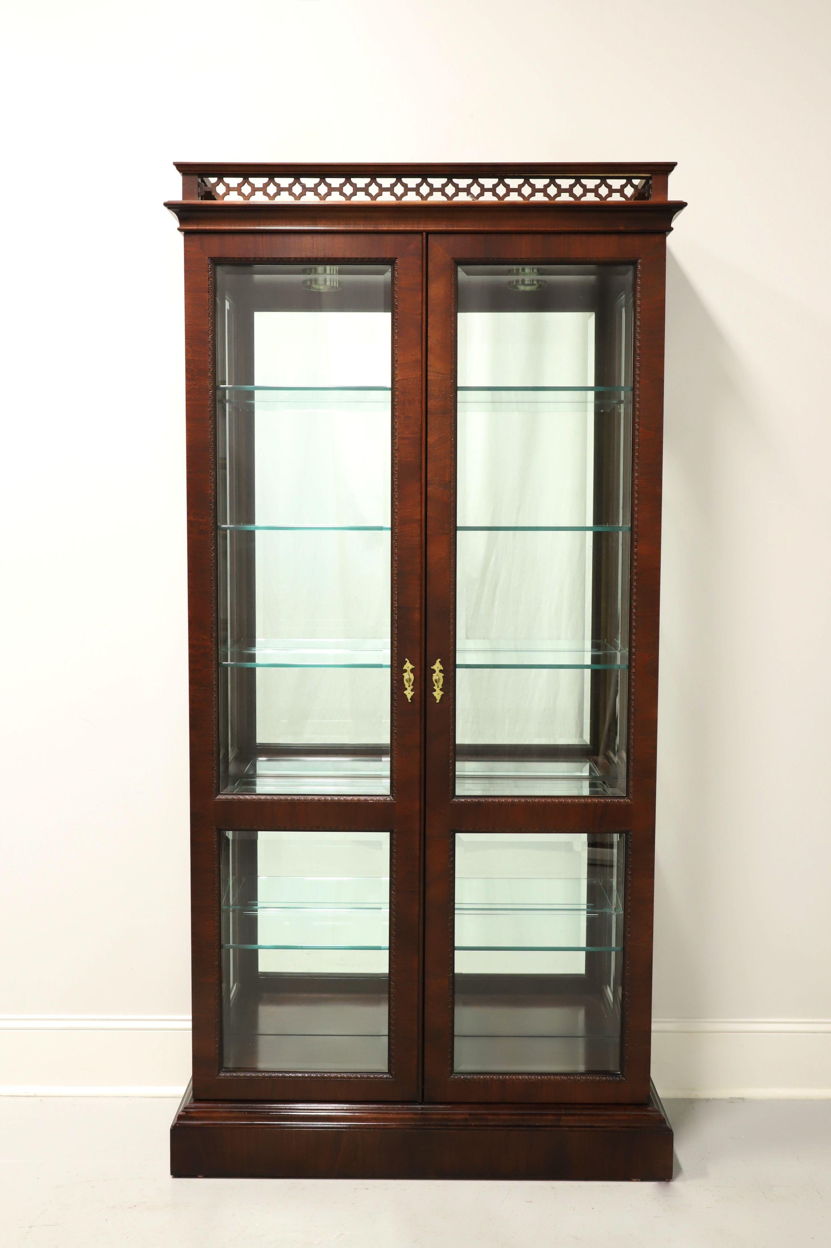 A Chippendale style curio display cabinet by Century Furniture, from their Claridge Collection. Solid mahogany with brass hardware, decorative fretwork gallery to top, beveled glass dual doors and beveled side panels. Lighted cabinet features a