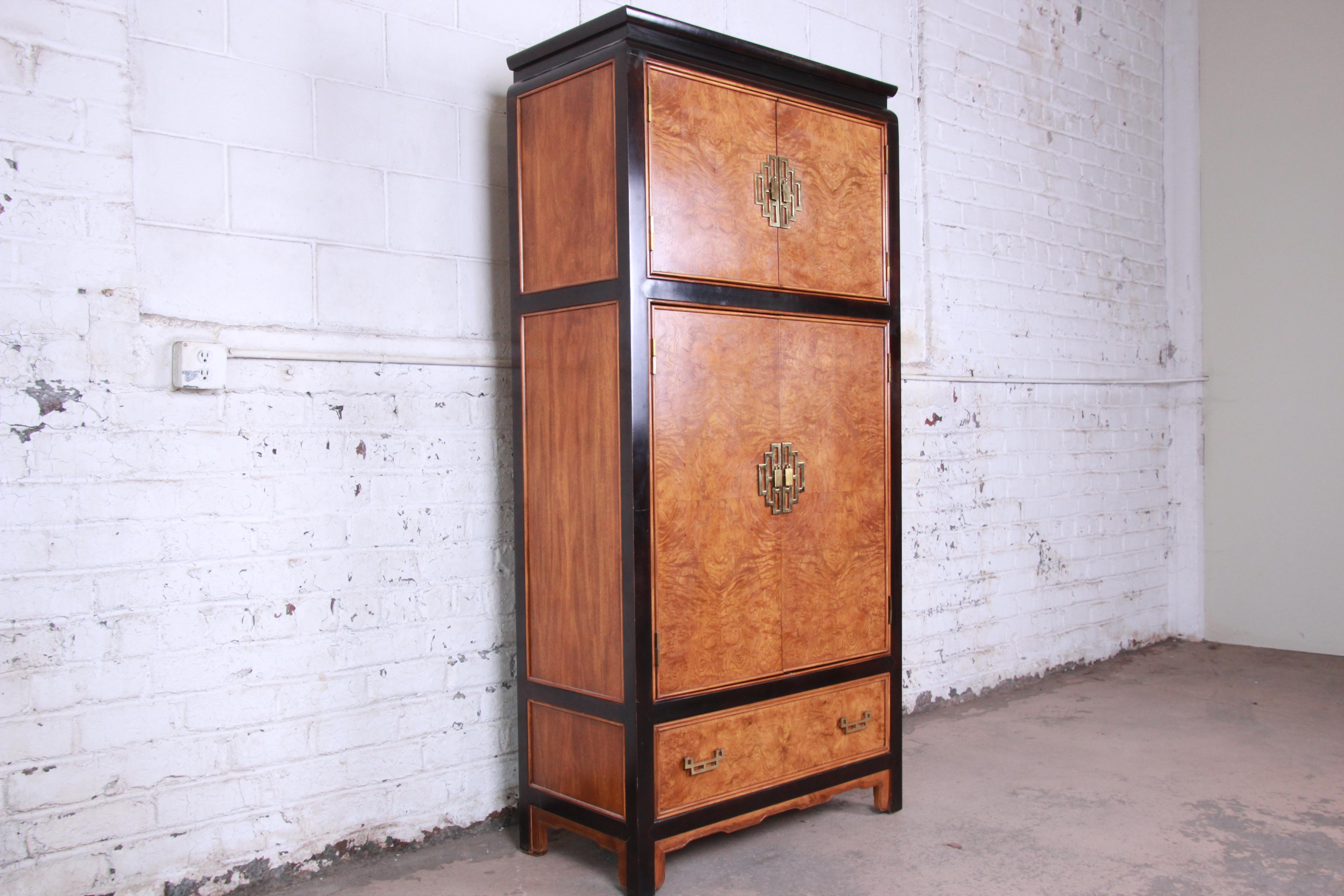 Offering a gorgeous Hollywood Regency chinoiserie black lacquered and burl wood armoire dresser by Century Furniture. The dresser has beautiful burl wood encased in black lacquered trim. The top of the armoire has two cabinet doors that open to a