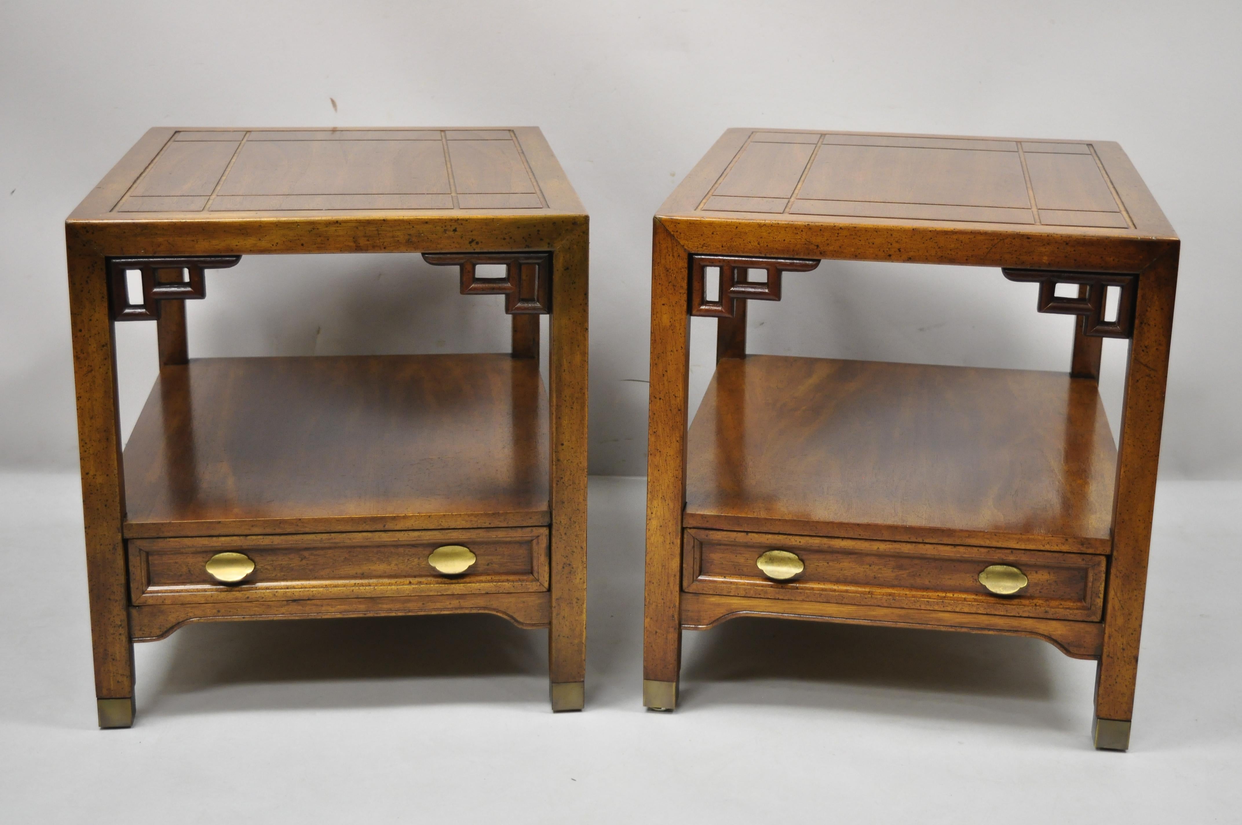 Century Furniture Chinoiserie fretwork wooden side lamp end tables - a pair. Item features carved fretwork corners, lower shelf, solid wood construction, distressed finish, nicely carved details, finished back, original stamp, 1 dovetailed drawer,