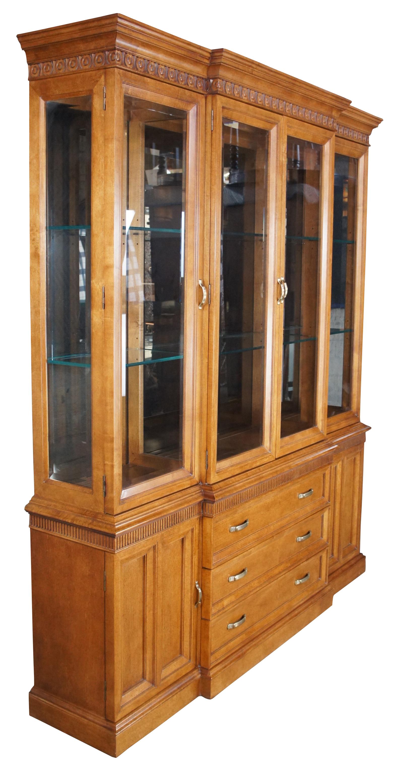 Vintage Century Furniture illuminating breakfront. Made of maple featuring French Neoclassical styling with bullseye banding, a fluted frieze, beveled glass and brass hardware. The base is centered by three drawers set between outer cabinets with