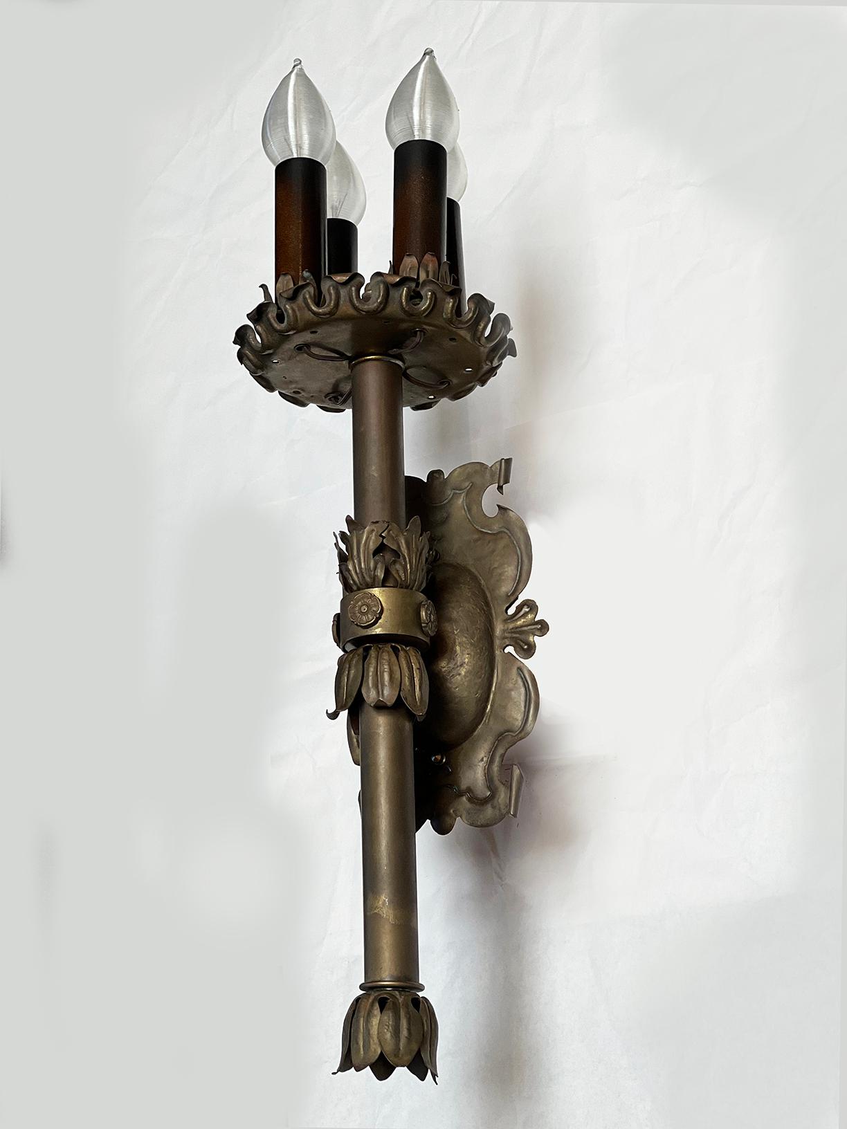 Century old brass wall sconce completely rewired with UL certified parts. Usually seen in iron, this ornate masterpiece is created out of pressed brass, aged to perfection. 4 x 60 watts. Silicone wrap bulbs included in final sale of this