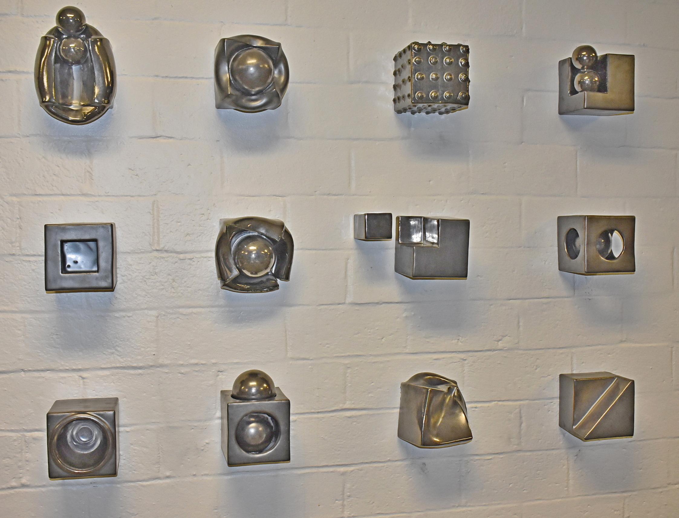 Ceramic 3D cube abstract modern wall art sculpture, 13 pieces. Suidan's cube series dates back to early 2000's. Collection of 13 cube sculptures by artist Kaiser Suidan. Various geometric forms in gun metal glaze. Wall mounted and signed on back.