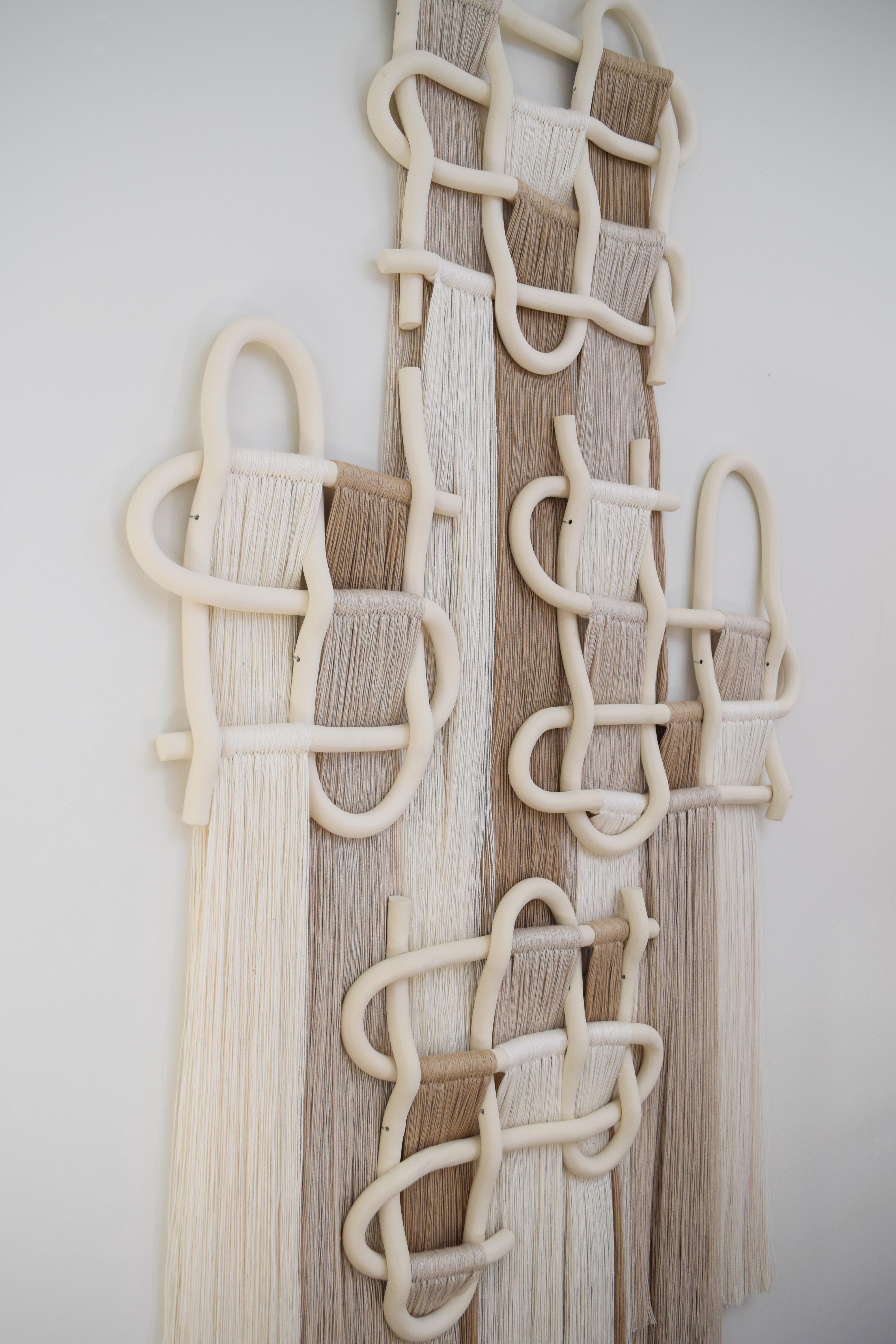 This item is in stock and ready to ship.

Four panel wall sculpture. Hand formed ceramic pieces in unglazed white stoneware with cotton fringe in white, off-white, and tan. Hanging wire is included on each panel. Ships with a small comb for fringe