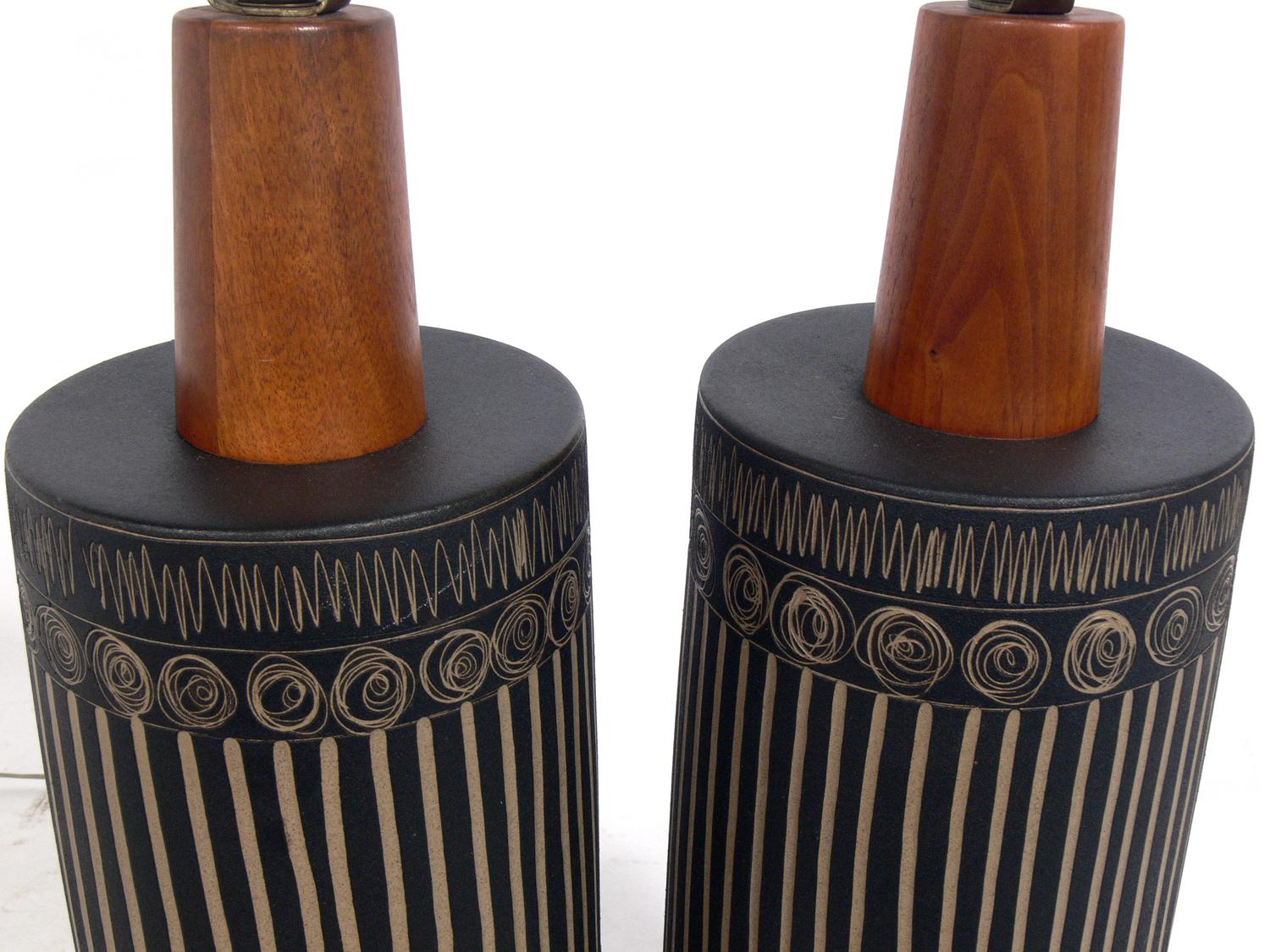 Pair of incised ceramic and walnut lamps, made by Gordon and Jane Martz for Marshall Studios, circa 1960s. Signed on the back. They retain their original walnut finials. Rewired and ready to use. The price noted below includes the shades.
  