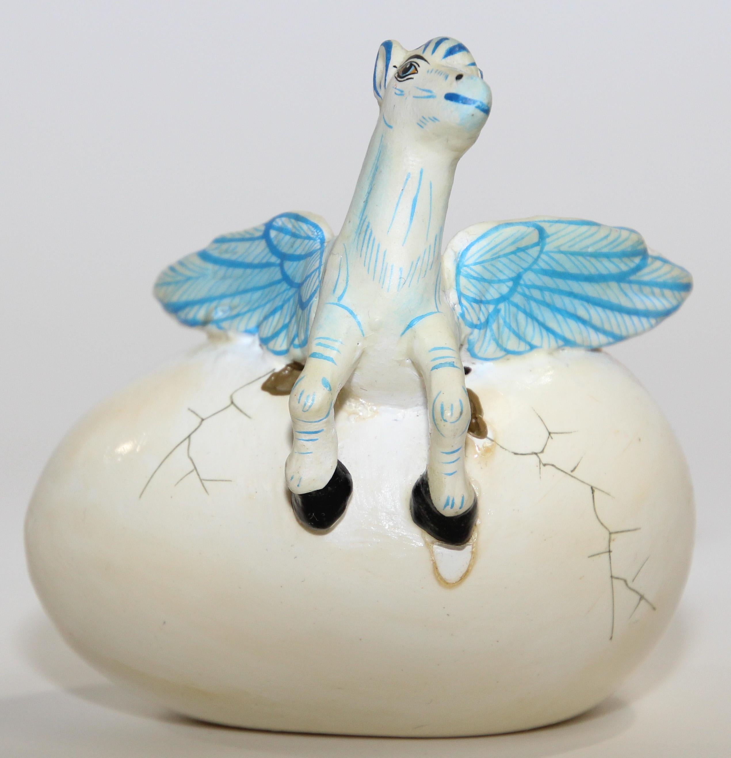 Small ceramic art sculpture with pegasus horse in egg hatching signed by Artist R. Miranda Mexico.
Mexican Tonala Folk Art Hatching Egg with baby horse.
Ceramic sculpture in egg depicting a small pegasus horse with wings breaking free from an egg.