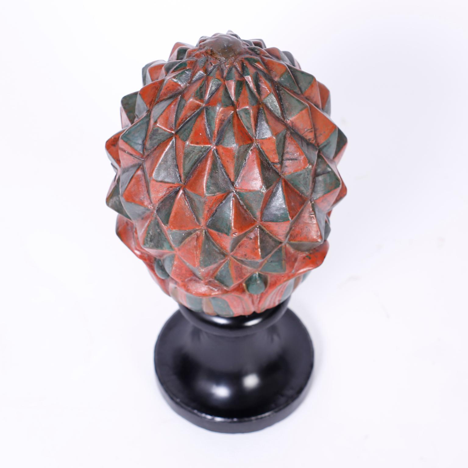 Late Victorian English ceramic stylized artichoke with a muted polychrome painted finish and presented on a Classic weighted ebonized stand.