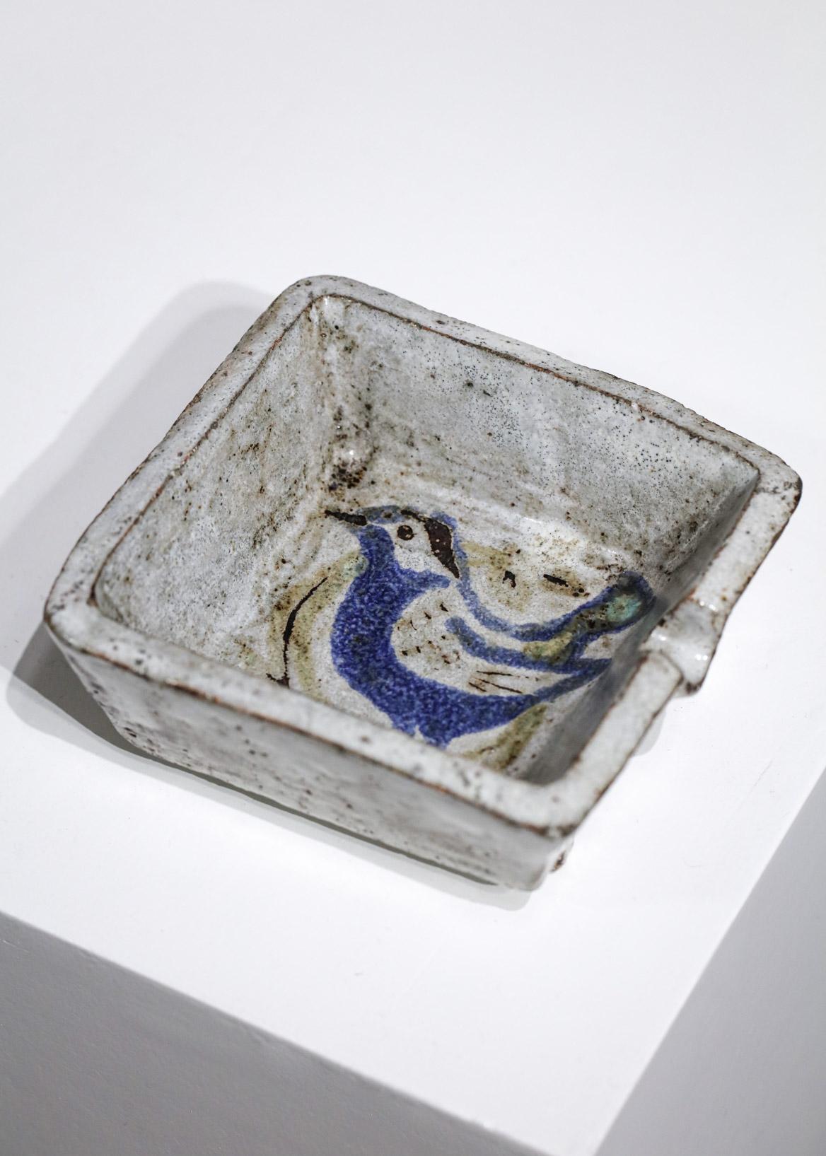 Quadratischer Aschenbecher aus den 50er Jahren von dem französischen Keramiker Jean Derval aus Vallauris. Sehr schöne Glasur auf dem gesamten Aschenbecher mit einer stilisierten Zeichnung eines Vogels in der Mitte. Signatur des Künstlers auf der