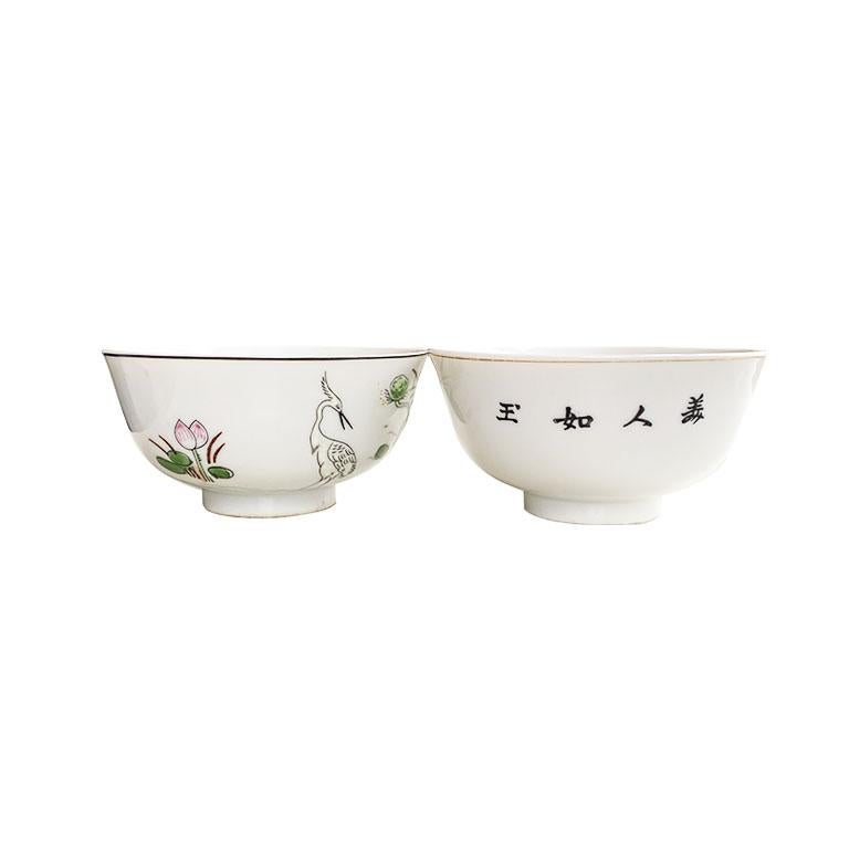 A superb set of two chinoiserie tea bowls, or cups. Each piece is decorated with hand painted designs of flowers, cranes and figures. The first cup, is our favorite, and features a white crane, standing among blooming pink and white lotus flowers.