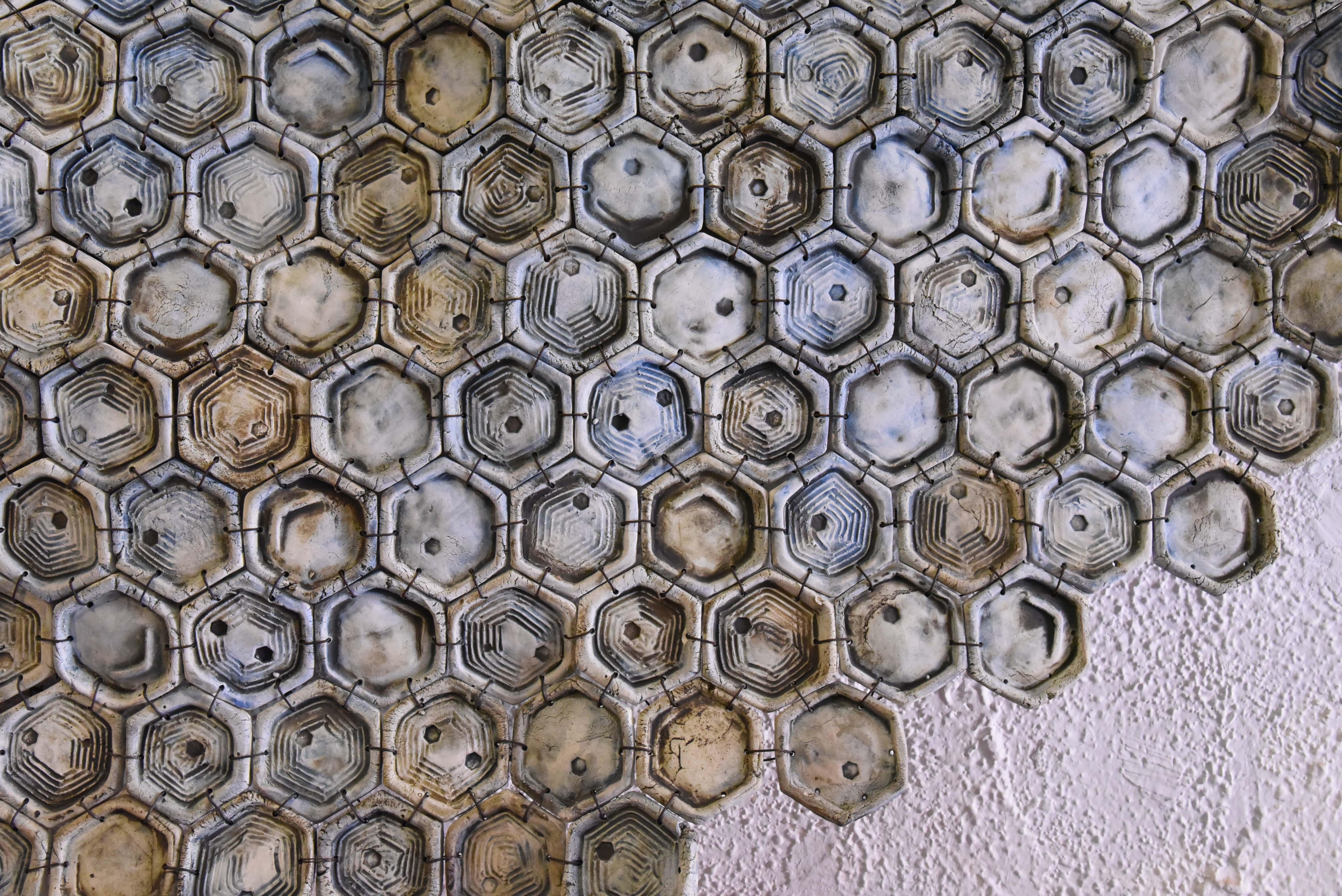 This piece is inspired by the geometry of the bees and their hive. Formed by 564 ceramic hexagonal pieces joined with wire, painted with earth and oxides. Piece by contemporary ceramist, Omar Hernández.