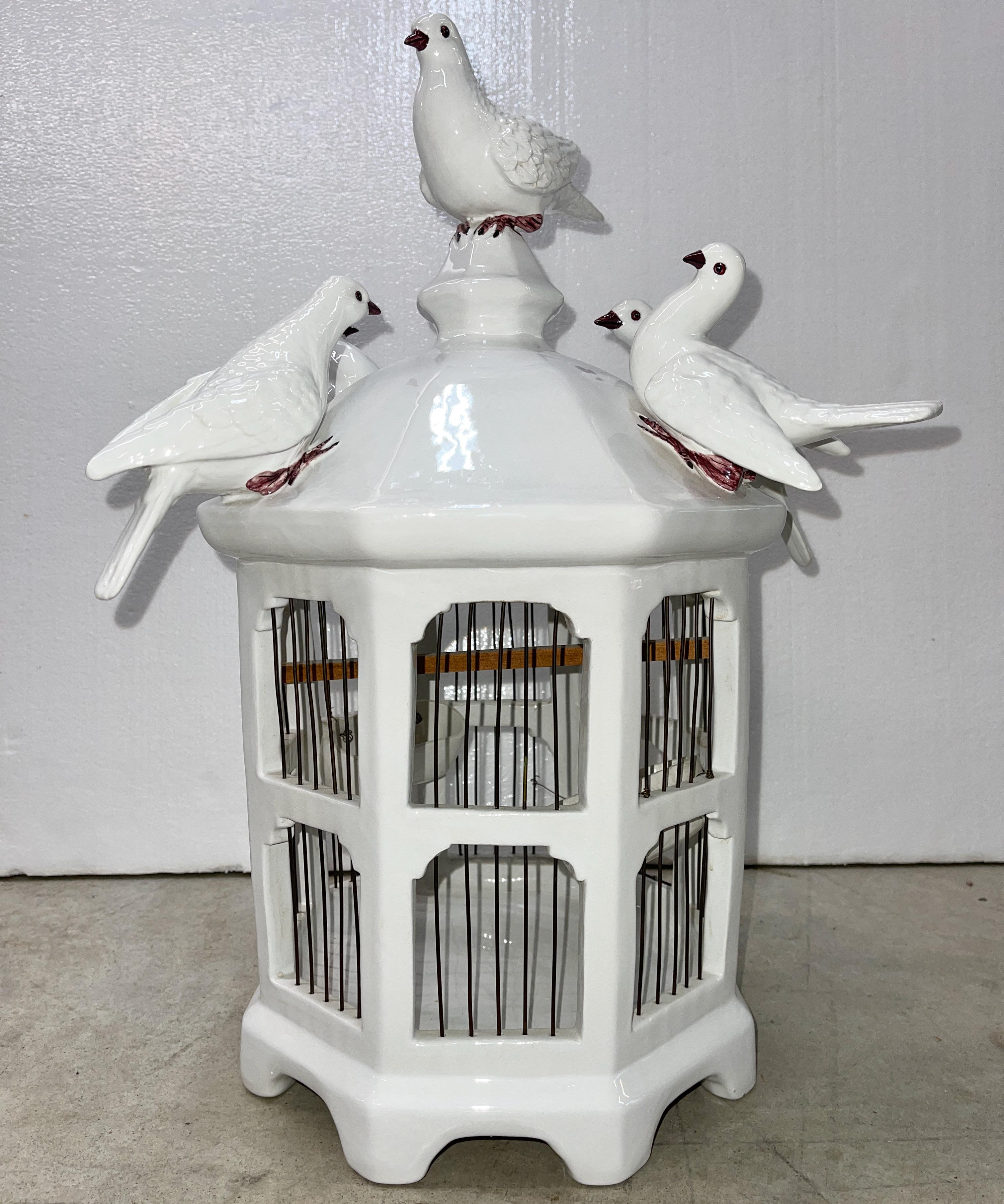 Centerpiece size ceramic and wire sculpture of five white doves seated atop a pagoda shape octagonal bird cage with two tiers of windows with wire 'bars' and two feeders.
Hand made in Italy circa 1970 by Ceramiche Artistiche R. Costa, Via Col di