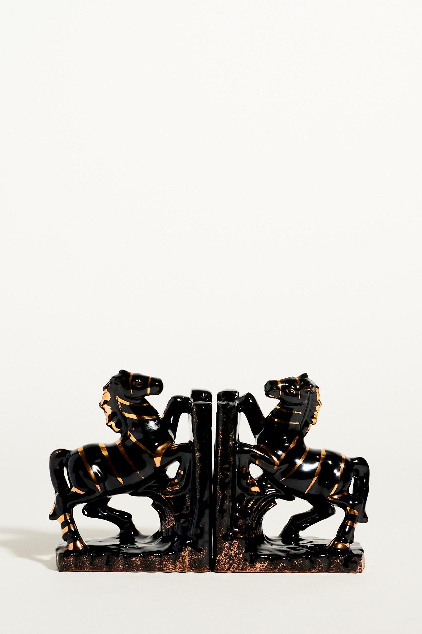 Black ceramic rearing horse bookends with metallic gold decorative effects.