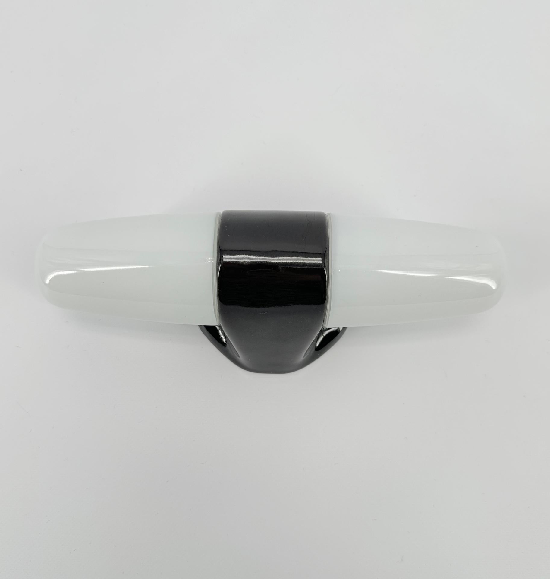 Wall light in black porcelain and opaline glass shades were designed by the German designer Wilhelm Wagenfeld, who studied at the Bauhaus school. 

This model dates from 1958 with sleek, round and elegant lines, a timeless design that will look
