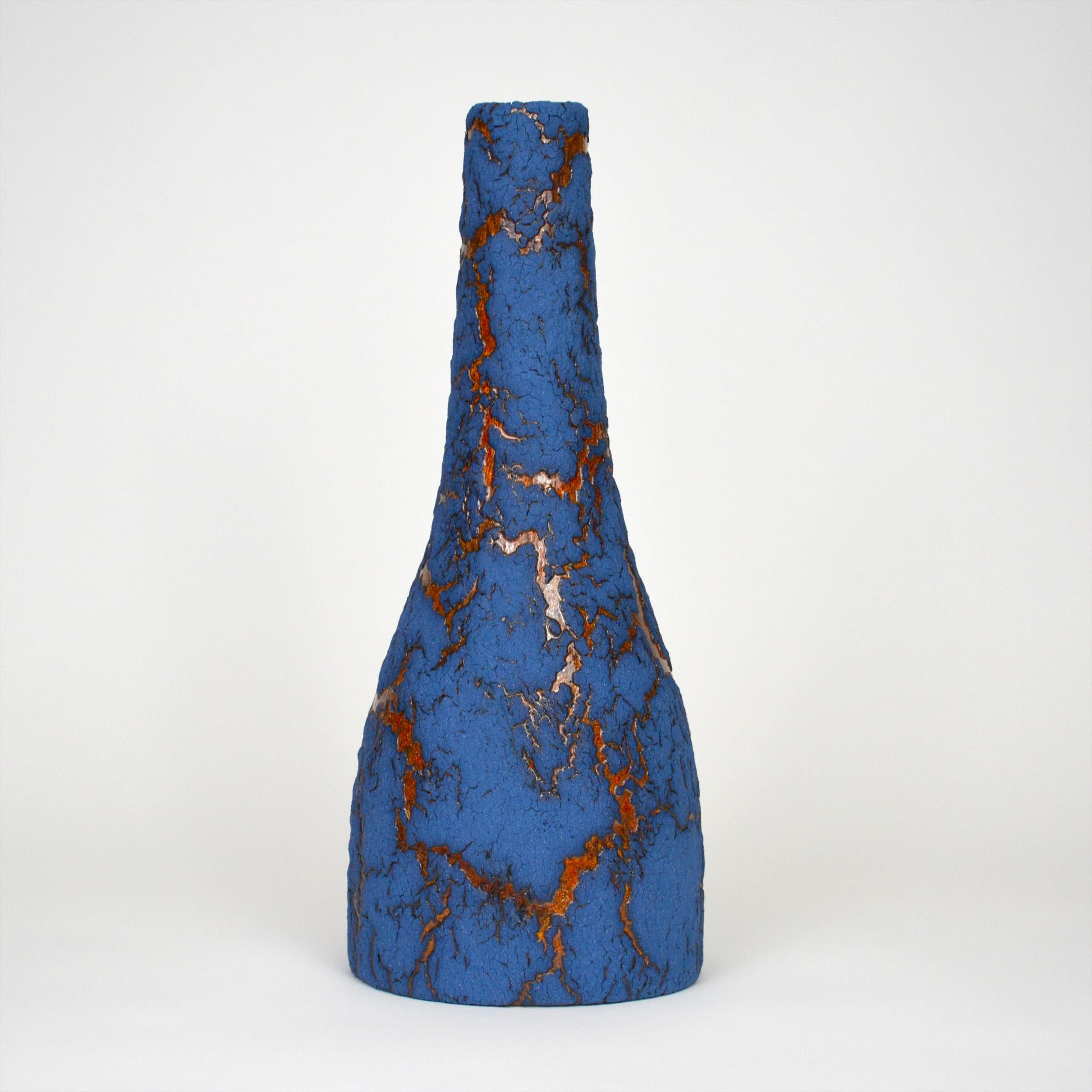 Ceramic bottle by William Edwards
Hand built earthenware vessel, fired multiple times to achieve a textured surface of random abstraction, matte blue with amber gloss microcrystalline glaze breaking through that sparkles in certain lighting