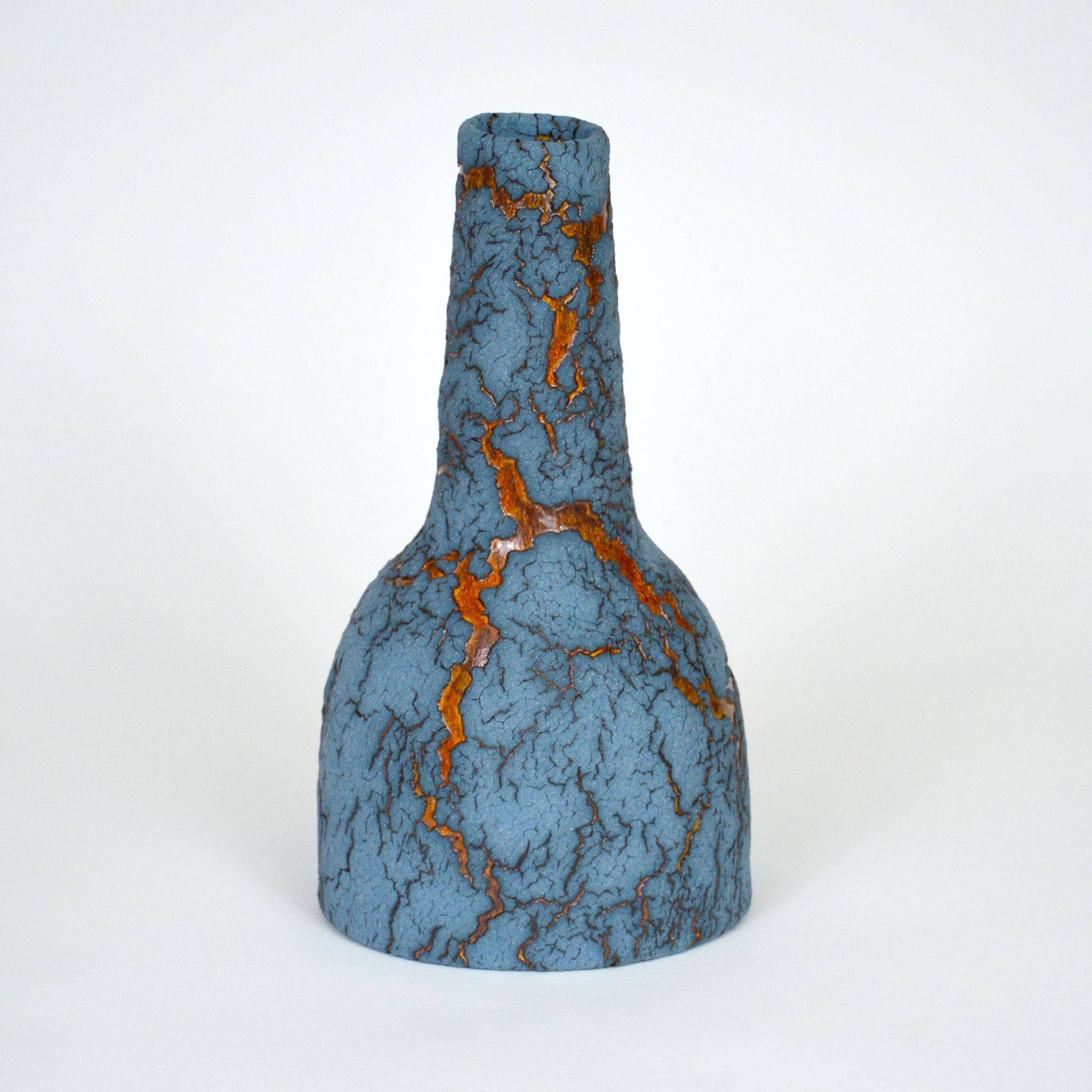 Ceramic Bottle by William Edwards
Hand built earthenware vessel, fired multiple times to achieve a textured surface of random abstraction, matte blue with amber gloss microcrystalline glaze breaking through that sparkles in certain lighting