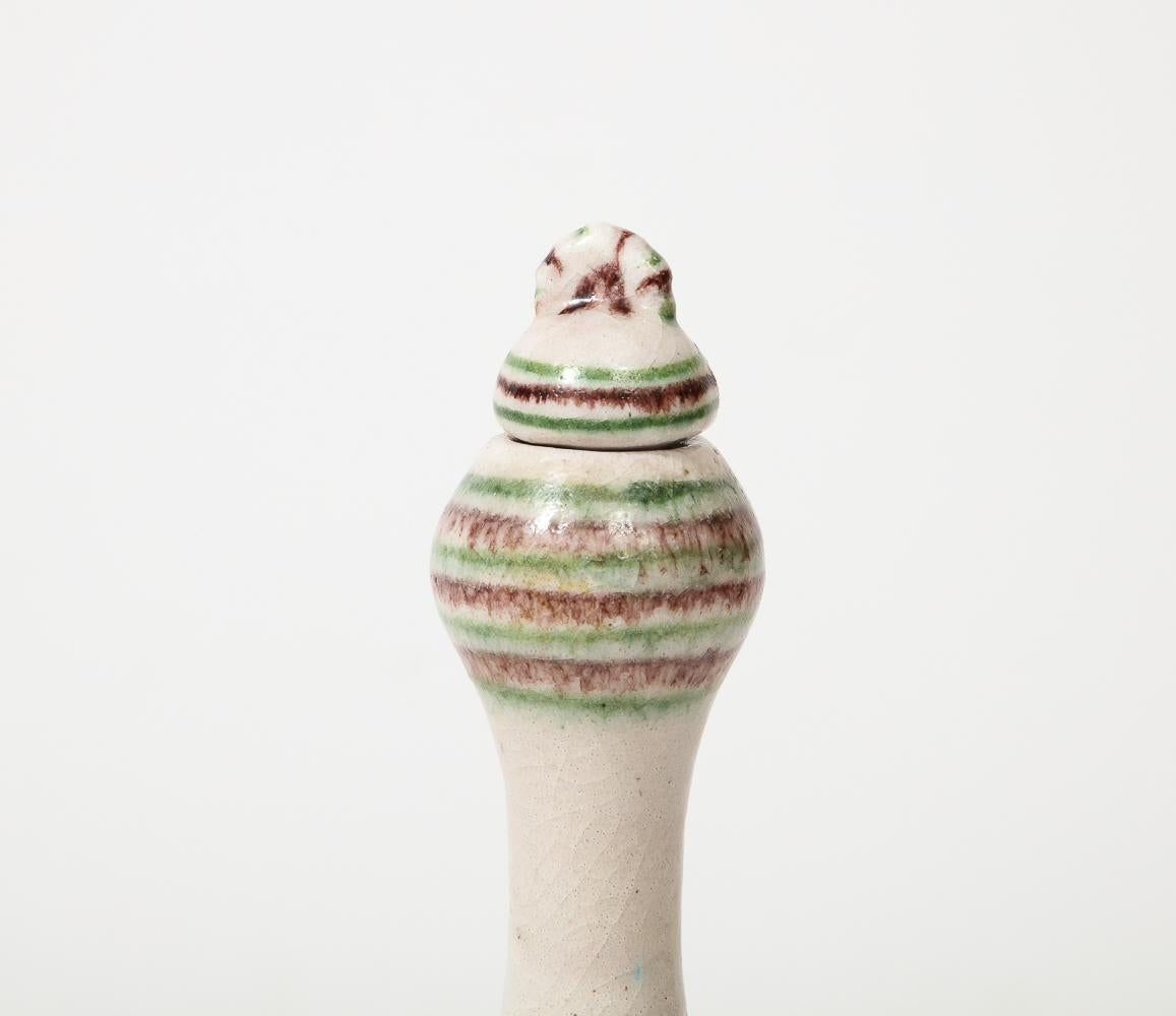 Stoneware. Bottle and stopper decorated with beige background. Green and brown linear decoration throughout. Similar bottle available with a yellow geometric pattern.