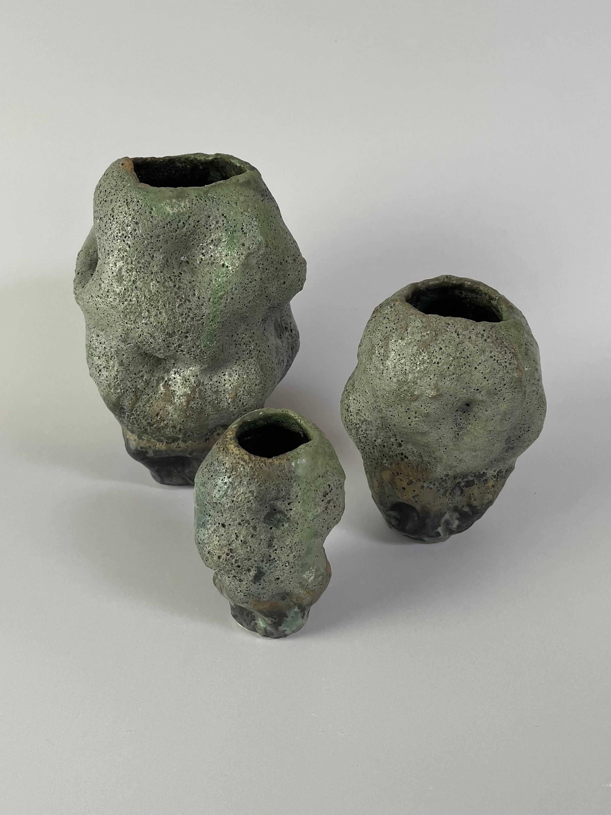 These three ceramic, boulder vases are an important piece of my work. I was making coil ceramic vases, and these morphed into more of an organic, textural surface. My pieces now have evolved from these pieces, where I use the same form, but pinch