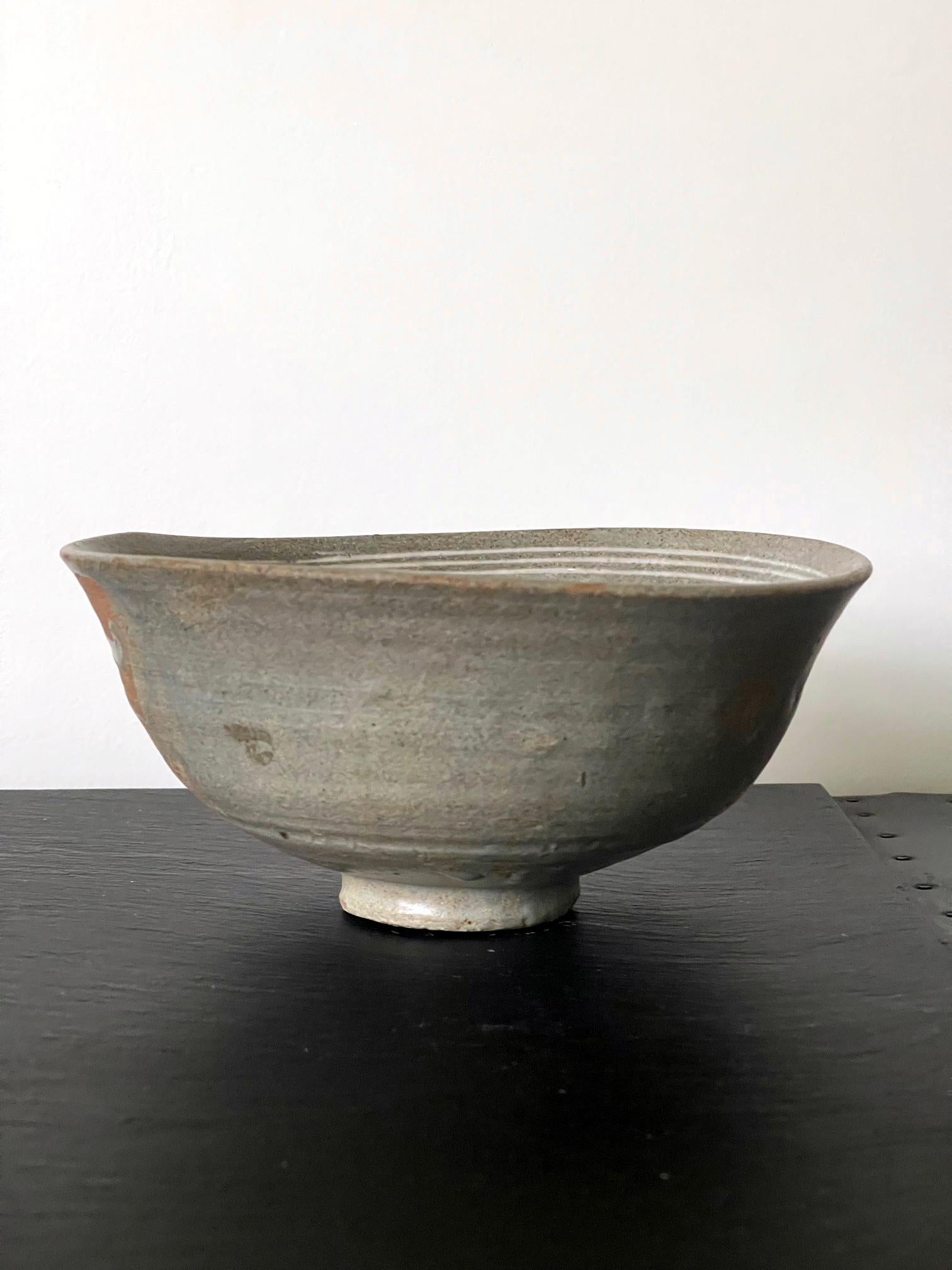 A Buncheong (also spelled as Punch'ong) stoneware tea bowl from Korea Joseon Dynasty circa 15-16th century. The conical shape bowl in the classical style was shows a slightly irregular form in its flared rim, standing on a small circular base. The