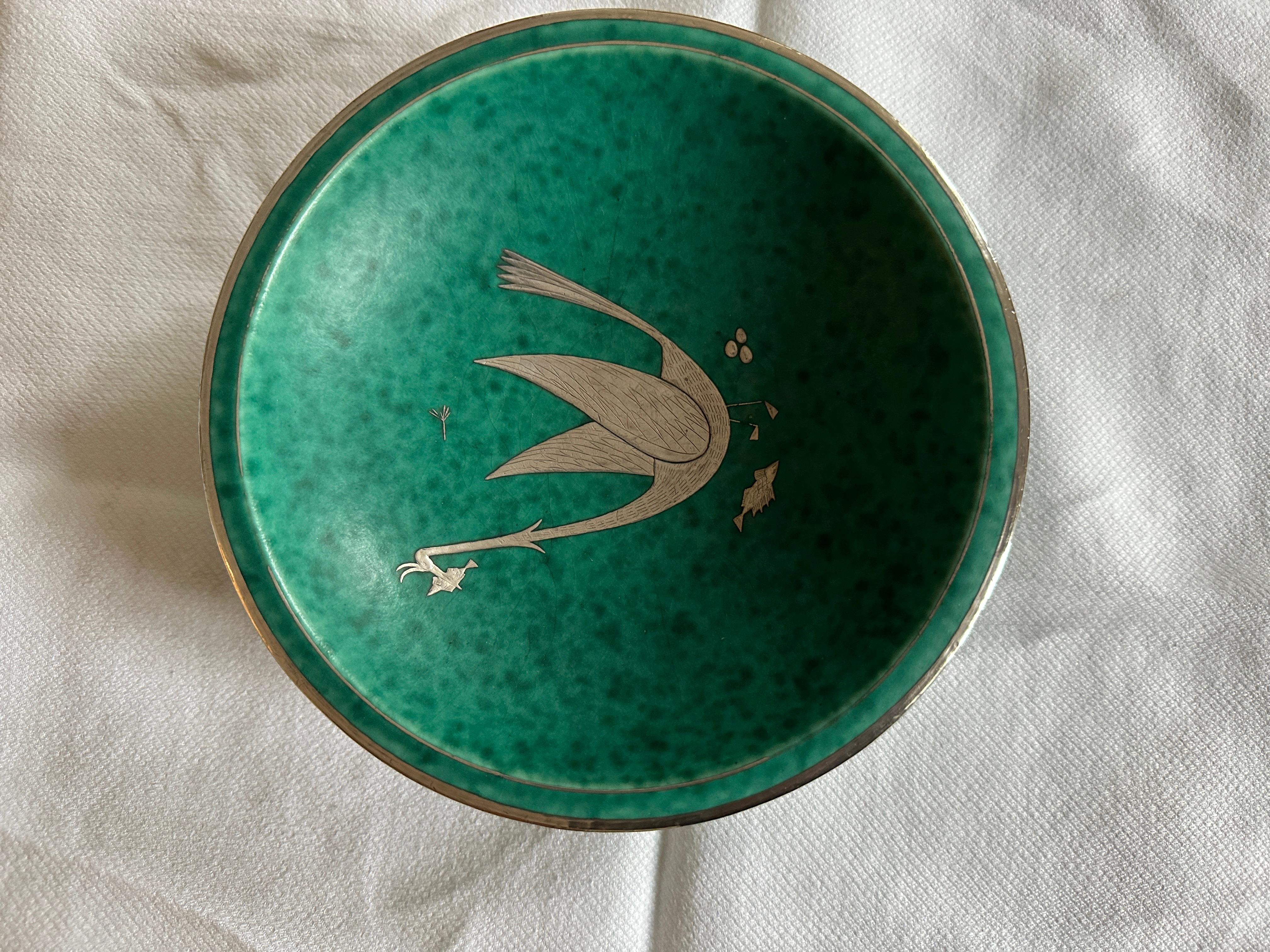 A bowl in ceramic with handmade silver inlay from the 1930s Argenta collection made by Wilhelm Kåge for Gustavsberg, signature underneath.
 The now iconic argenta stoneware collection, with its green glaze and silver decoration, is one of Wilhelm