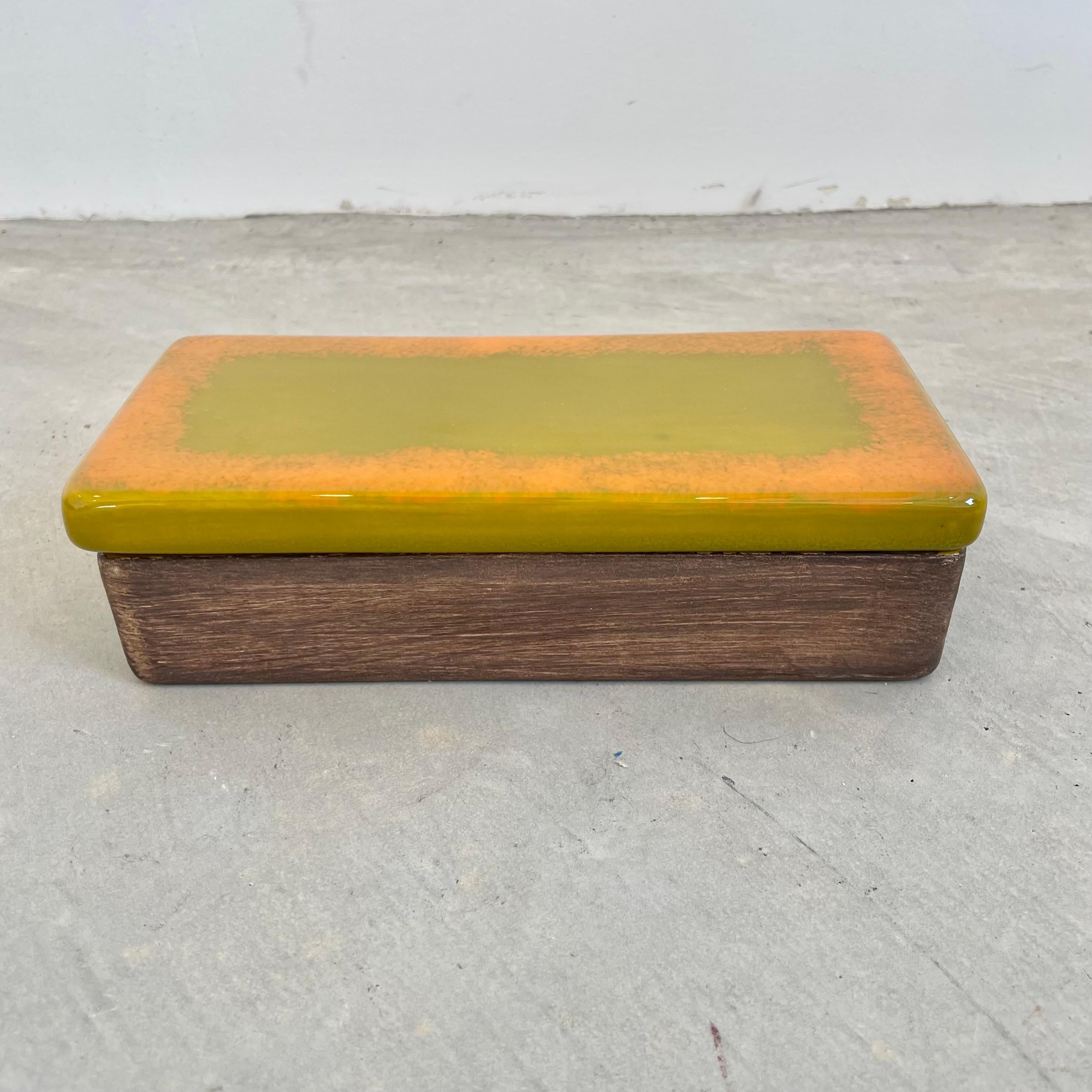 Glaze ceramic box made in Italy, circa 1970s. Slime green glaze along the top with an orange ring around the edge of the lid. Base is painted a matte brown. Green glaze covers the inside of the box. Great vintage condition. Fun stash box and