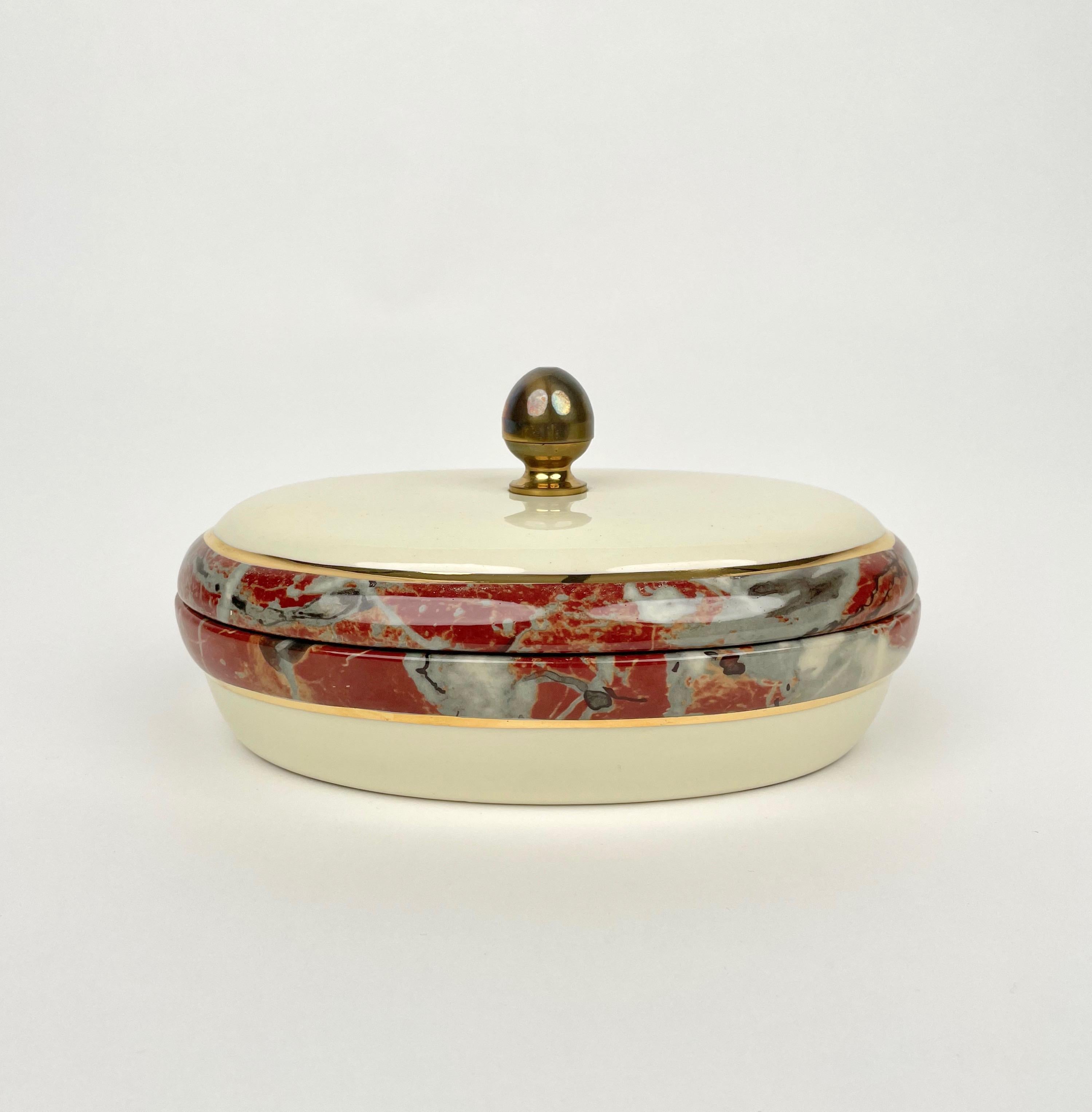 Oval box in ceramic with marble effect borders and brass handle by Tommaso Barbi for B Ceramiche made in Italy in the 1970s. 

The original label is still attached on the bottom, as shown in the photos.