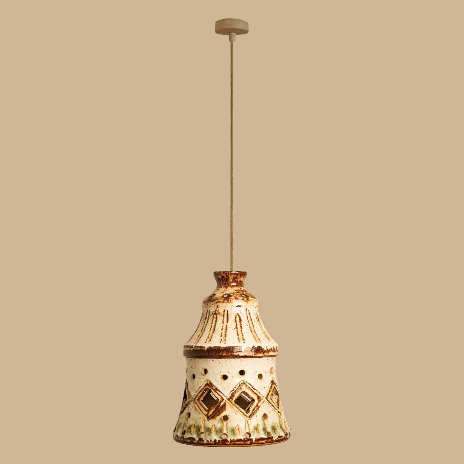 Suspension élégante en céramique fabriquée au Danemark. La lampe est fabriquée en céramique marron et beige avec des accents vert clair et présente un motif géométrique de lignes et de trous, ce qui lui permet de s'illuminer magnifiquement.

Une