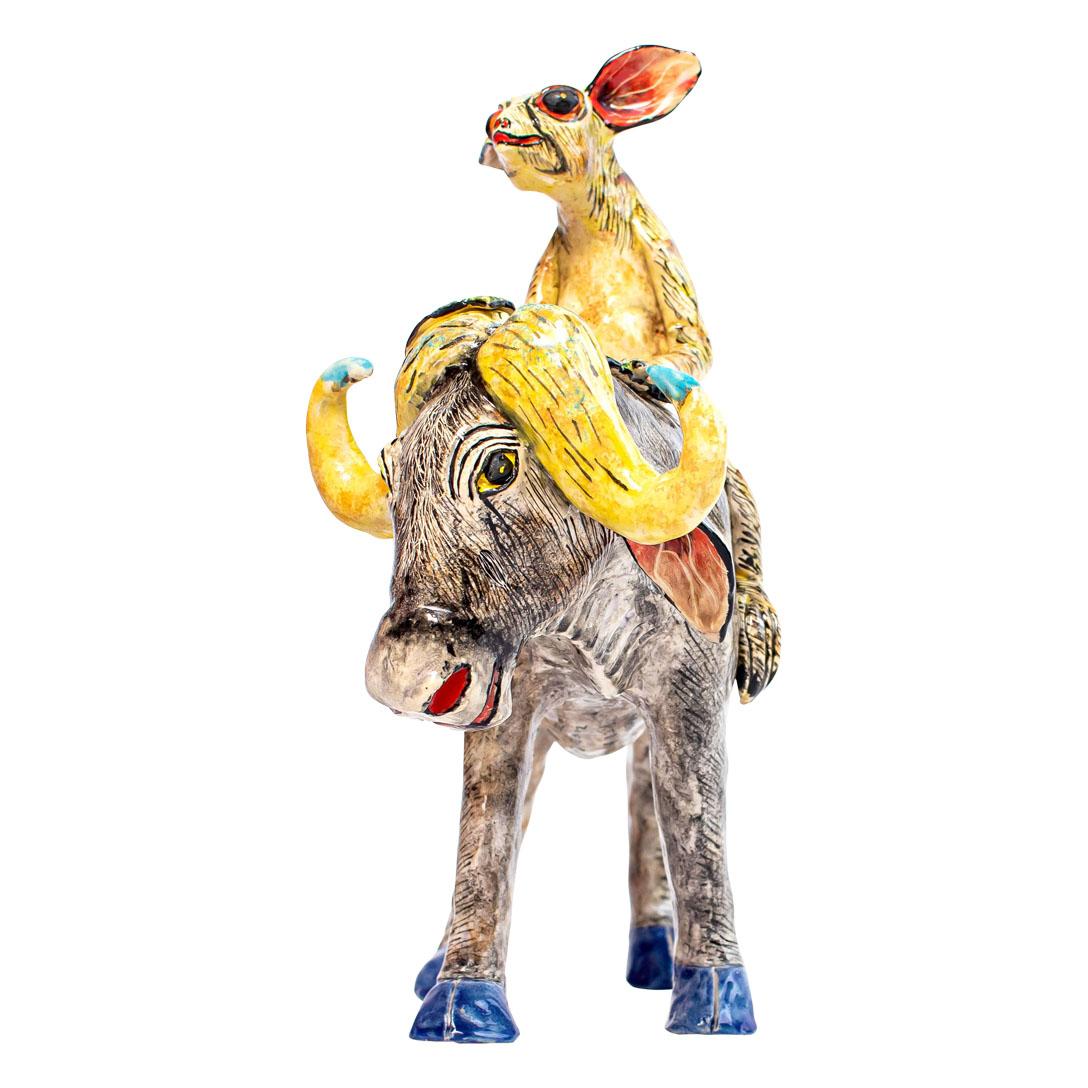 The Ceramic Buffalo Bush Baby Rider, a remarkable piece from Zimele Ceramics, is a vivid testament to the studio's artistic vision and cultural depth. Hand-sculpted by Nokubonga and hand-painted by Victor, this charming creation stands 10 inches