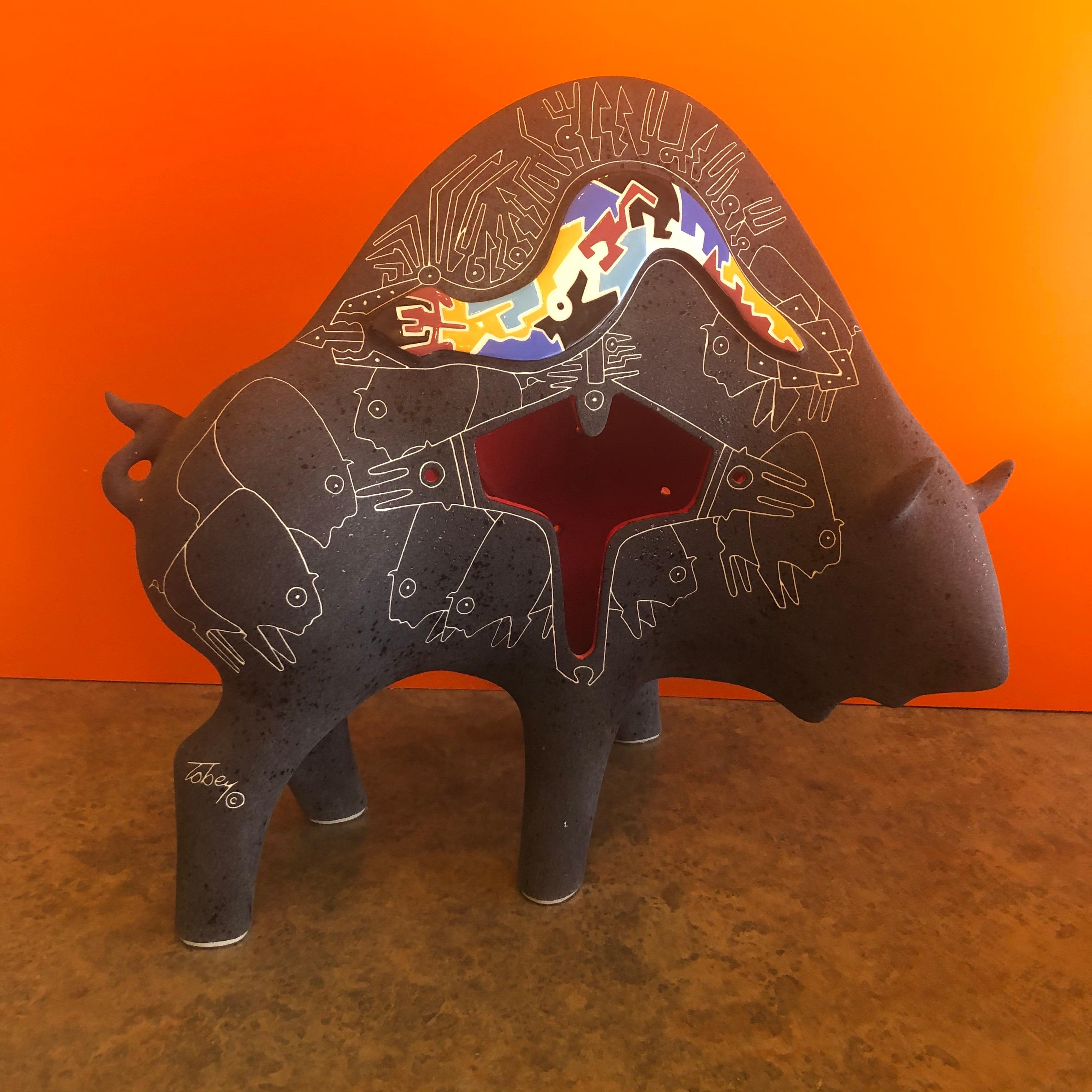 A very cool, unique and whimsical ceramic bull by husband and wife artists, Gene & Rebecca Tobey, circa 1990s. The piece has a matte black finish with white hieroglyphics and colorful patchwork; it measures 11