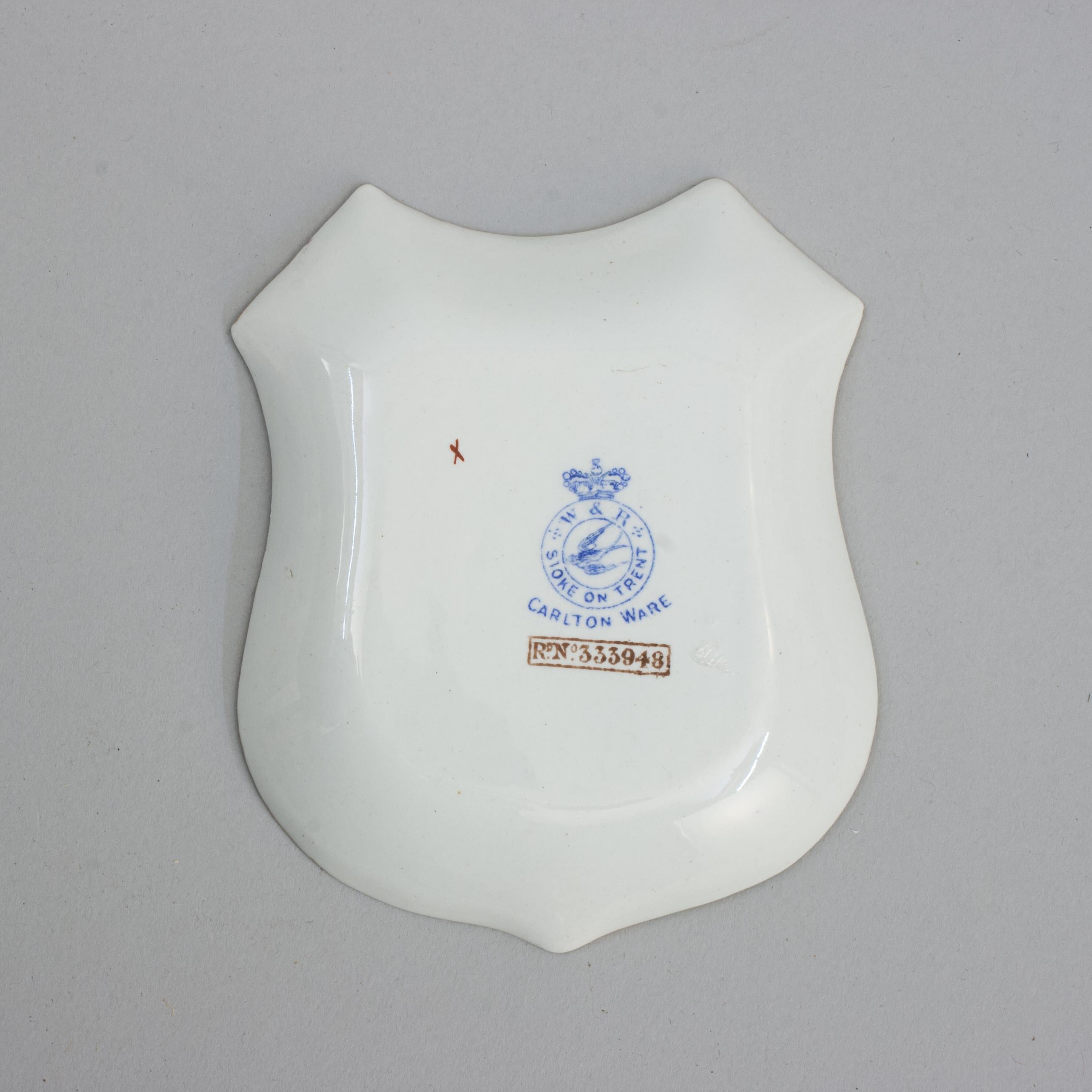 Wiltshaw & Robinson Carlton Ware Golf Pin Tray.
A ceramic Carlton Ware pin tray with a golfing scene and gilt rim. The golf scene shows one golfer dressed in a red coat about to strike the ball watched by another player and a caddy. The bottom
