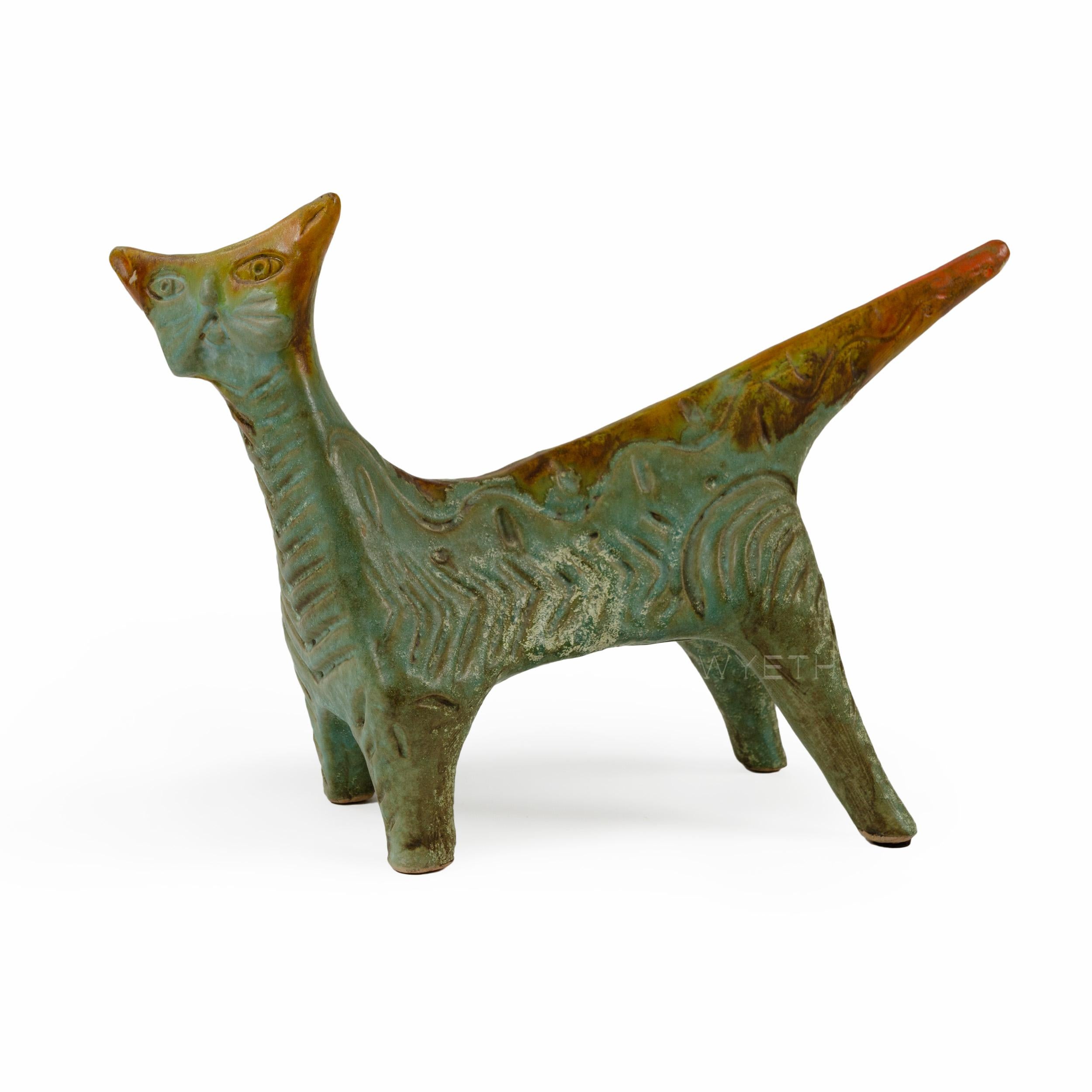 A ceramic cat with an orange and green glaze inscribed with a graphic design.