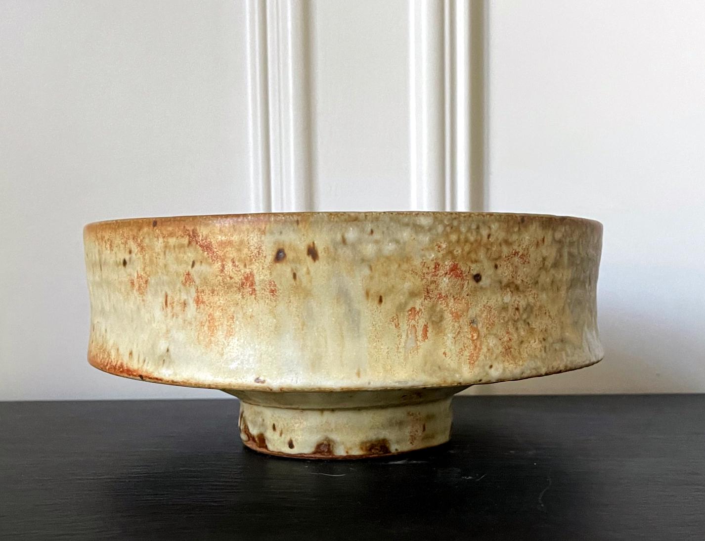 A very fine studio ceramic vessel with exceptional sculptural form by American potter Warren Mackenzie (1924-2018). In a barrel shape with slightly concaved wall, the centerpiece stands on a circular foot. The stoneware was glazed in a greenish