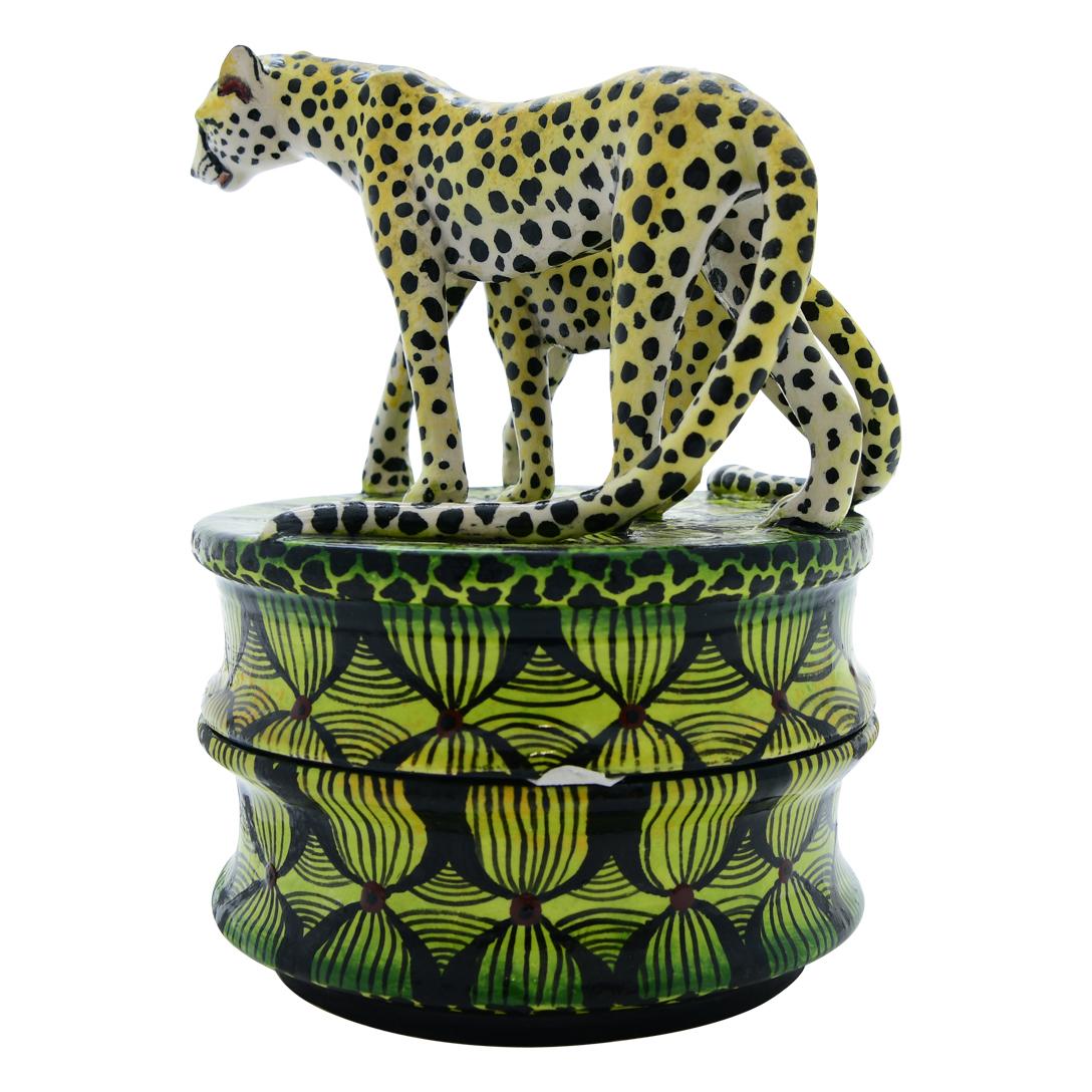 Senzo Duma Ceramics presents a ceramic Cheetah jewelry box, standing 4 inches tall with dimensions of 5 inches in length and 4 inches in width. Hand-sculpted by artisan Lefu and adorned with intricate hand-painted details by Gugu, this piece