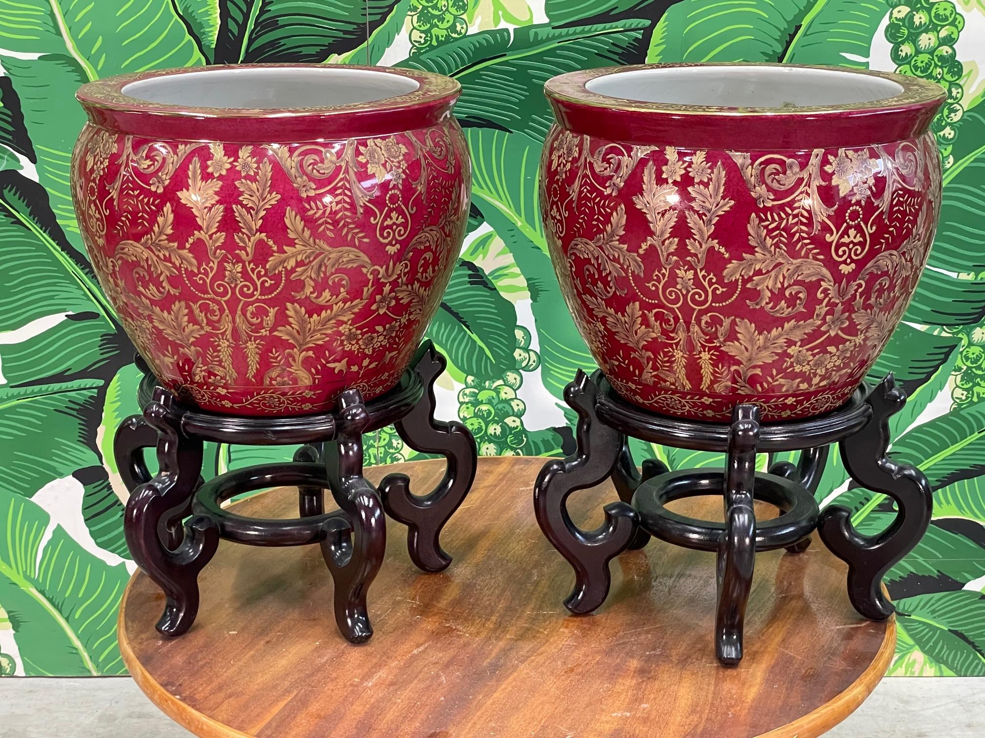 Pair of large Asian ceramic planters on wood stands feature hand painted acanthus leaves and flowers as well as fish and underwater foliage on the inside of the pot. Good condition with no chips or cracks. Possible minor imperfections consistent
