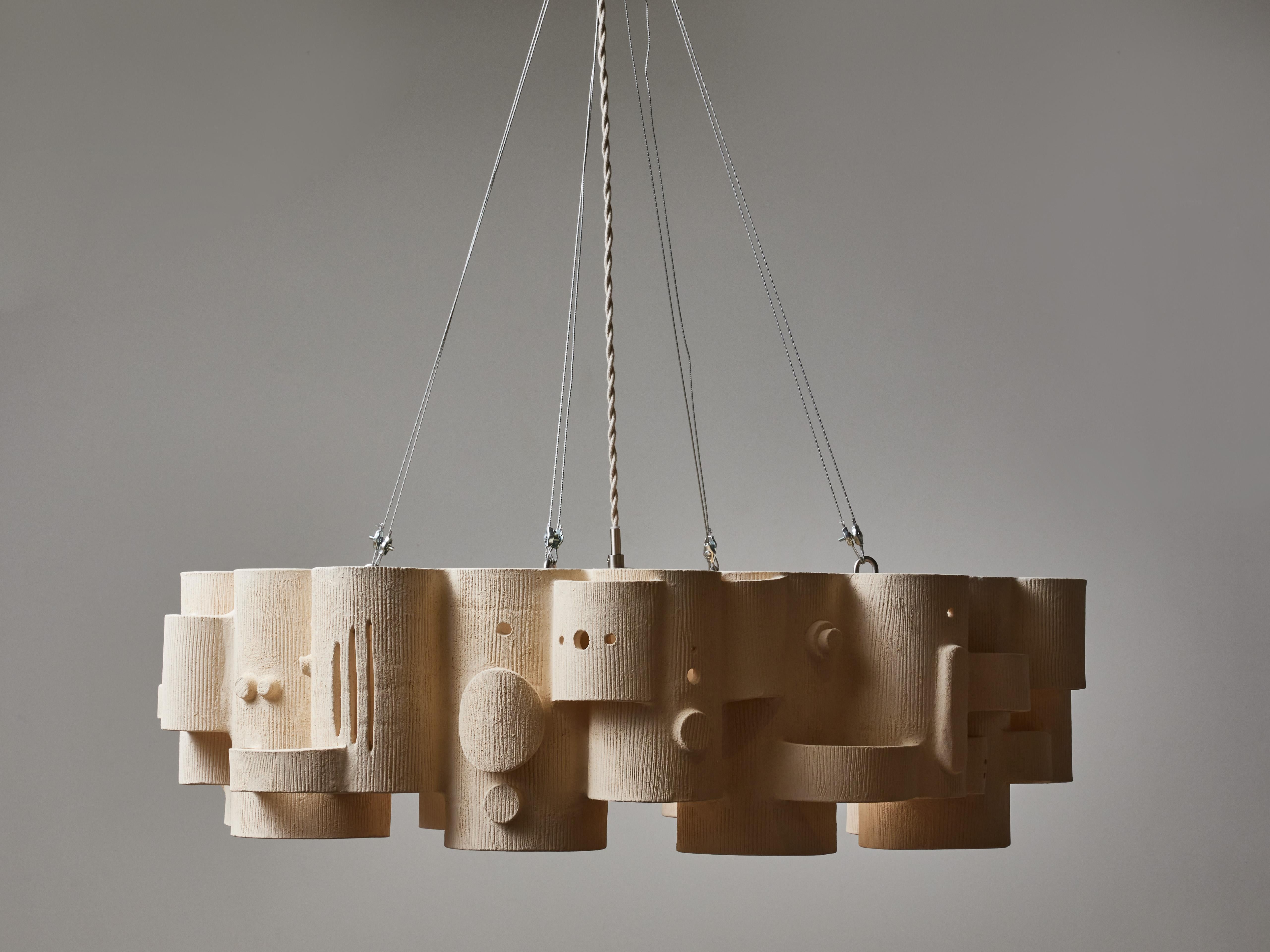 Ceramic chandelier made by the french artist Olivia Cognet, made of different sized cylinders put together covered with decorative elements.

Since moving to Los Angeles in 2016, French artist and designer Olivia Cognet has focused on ceramics as