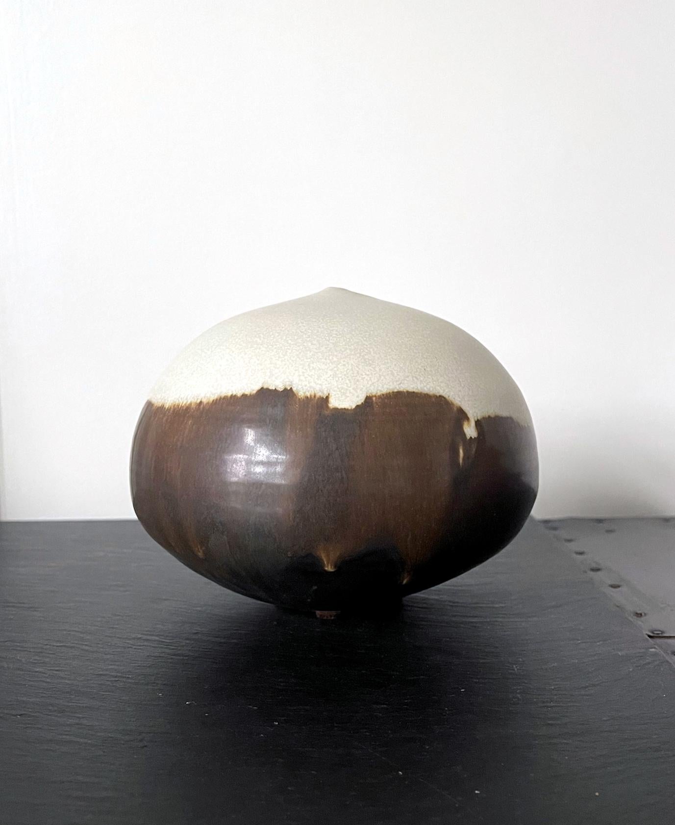 A ceramic closed-form pot by Japanese American artist Toshiko Takaezu (American, 1922 - 2011). This iconic form by the artist takes the simplest organic form but is instilled with a deeper philosophy. The void space and the air trapped inside of the