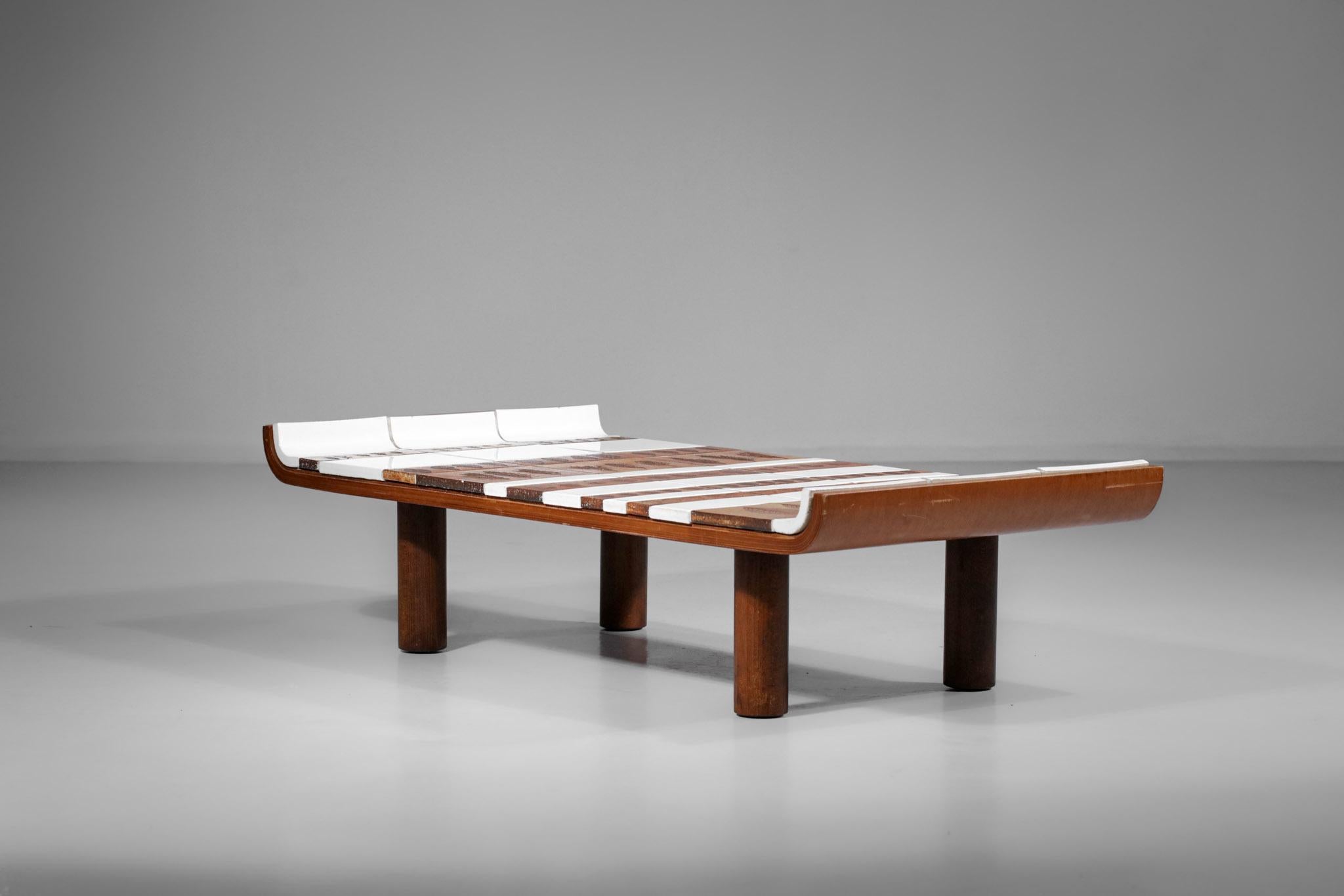 Wood and ceramic coffee table from the 50's by the French ceramist Roger Capron. Original because of its shape curved upwards, the top is covered with glazed ceramic in shades of brown and white, with inlays of 