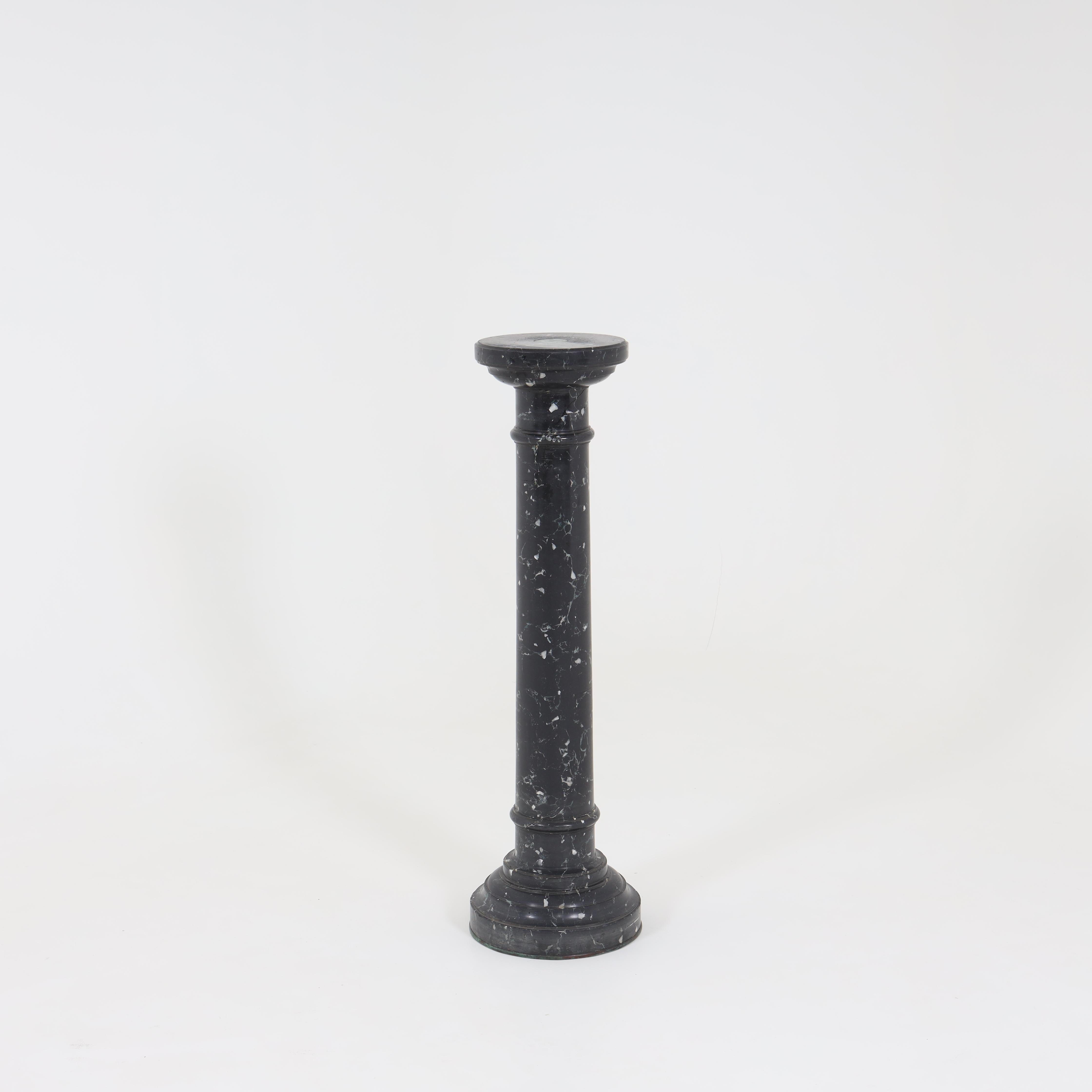 Column on profiled base and smooth shaft made of black and white marbled ceramic.