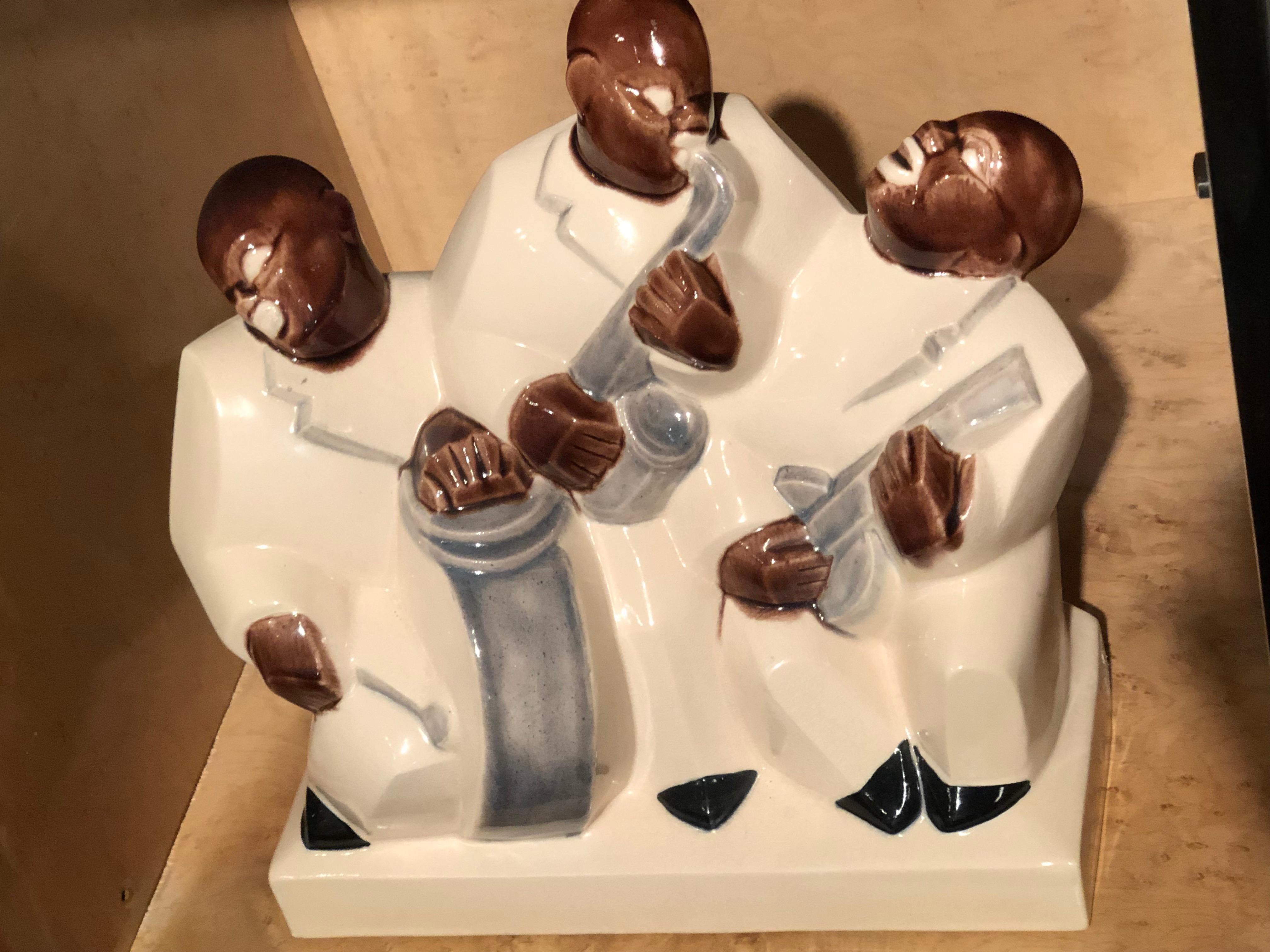 Rare sculpture of black jazz trio sculpted in ceramic and styled from the Art Deco era, circa 1930. This rare sculpture depicts a European view of the hot jazz age, Horn, banjo and drums. All 3 images are integrated with an angular cubist style.