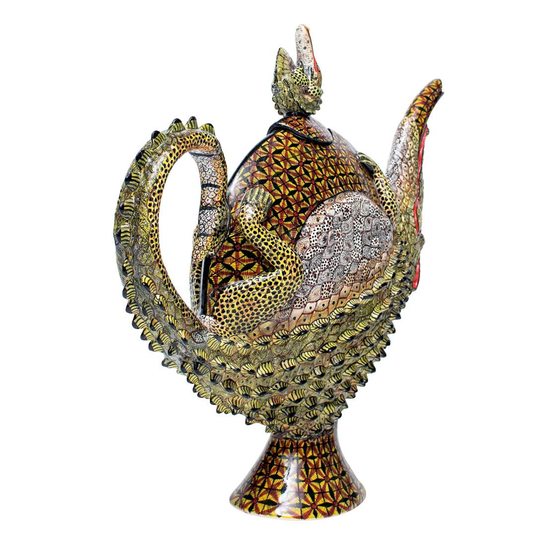 Tetera Cocodrilo: Pintada a mano por Winnie Mchunu y esculpida por Sbusiso Ndaba

La Tetera Cocodrilo es una extraordinaria pieza de arte en cerámica de Sudáfrica, que fusiona maravillosamente la funcionalidad con el vibrante espíritu de la vida