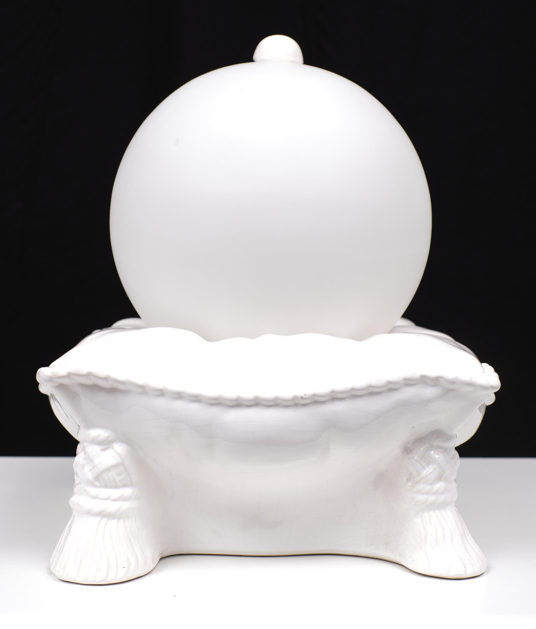 Love this very unusual Table lamp. White in the shape of a cushion Ceramic
base, comes with tassels on the corners. On top a Satin white Globe.
Unique piece.