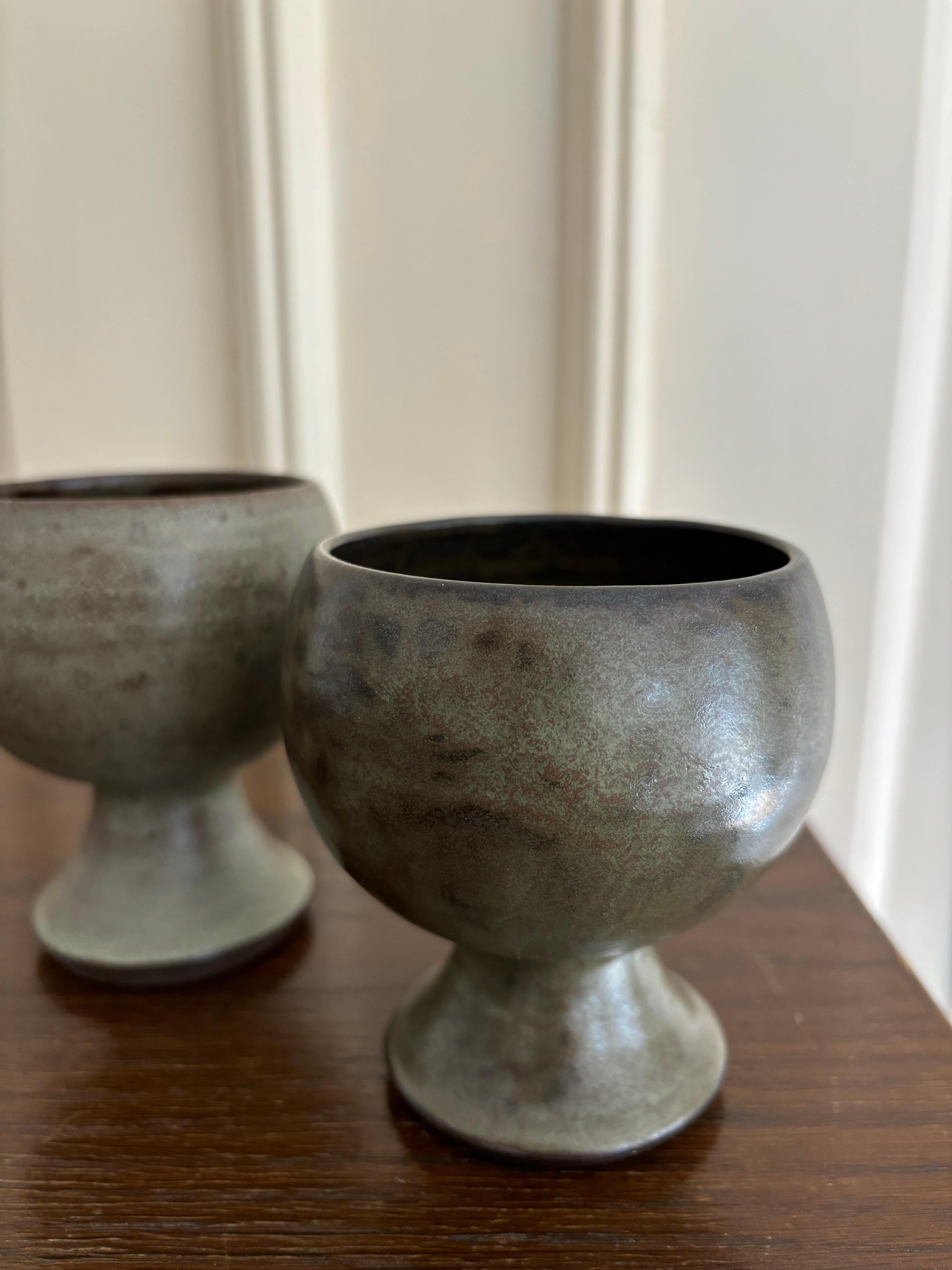 A unique set of two hand-thrown and beautifully glazed vases / cups by ceramic artist Cilia Bork Lassen on the small island of Orø in 1981. Dark earthy brown, black and green colors in a beautiful cloudy, speckled mix. Signed and dated by the