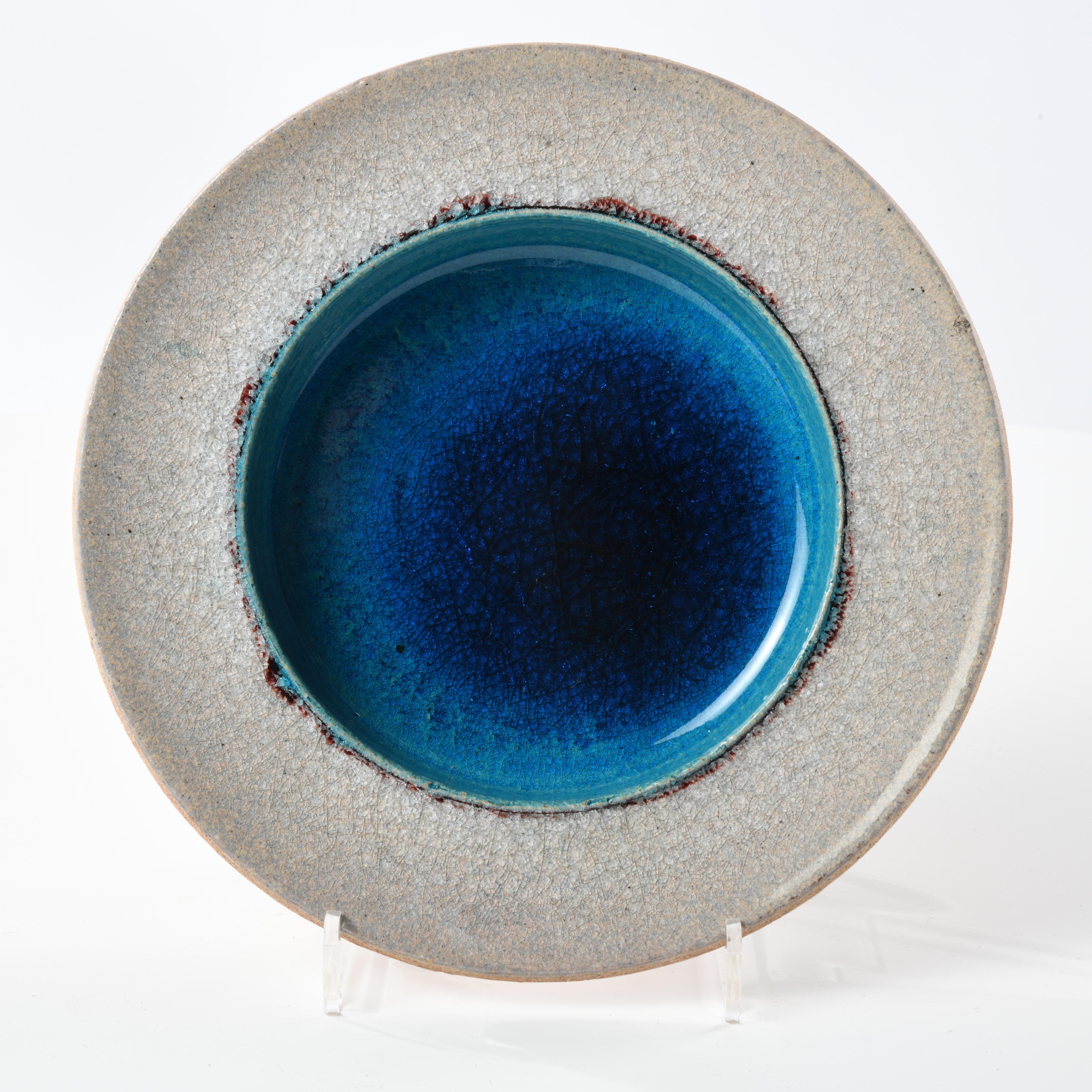 Small stoneware dish glazed in the 1960s in Denmark, signed Nils Kähler (1906-1979). Beautiful two-tone glaze, light grey with deep midnight blue and turquoise tones. Signature and label underneath. 
The Kähler factory was founded in Denmark in 1839